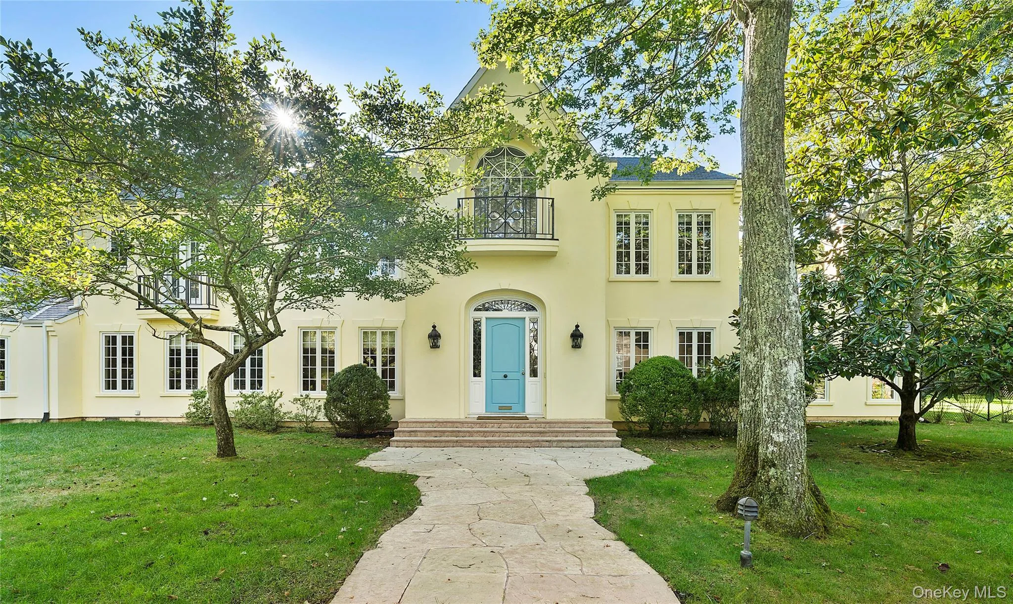 View of front of home featuring a front yard, stucco siding, and a balcony View of front of home featuring a front yard, stucco siding, and a balcony