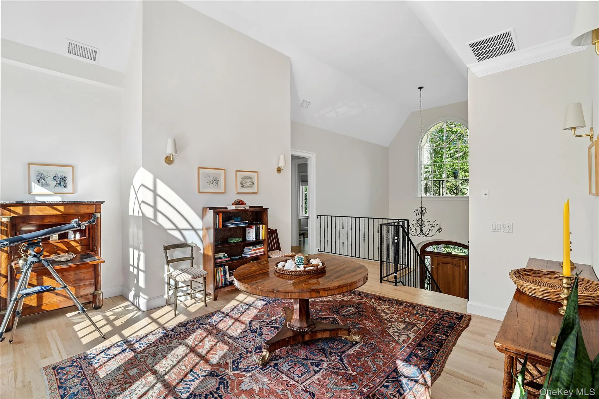 Sitting room with an upstairs landing, light wood-style floors, and high vaulted ceiling Sitting room with an upstairs landing, light wood-style floors, and high vaulted ceiling