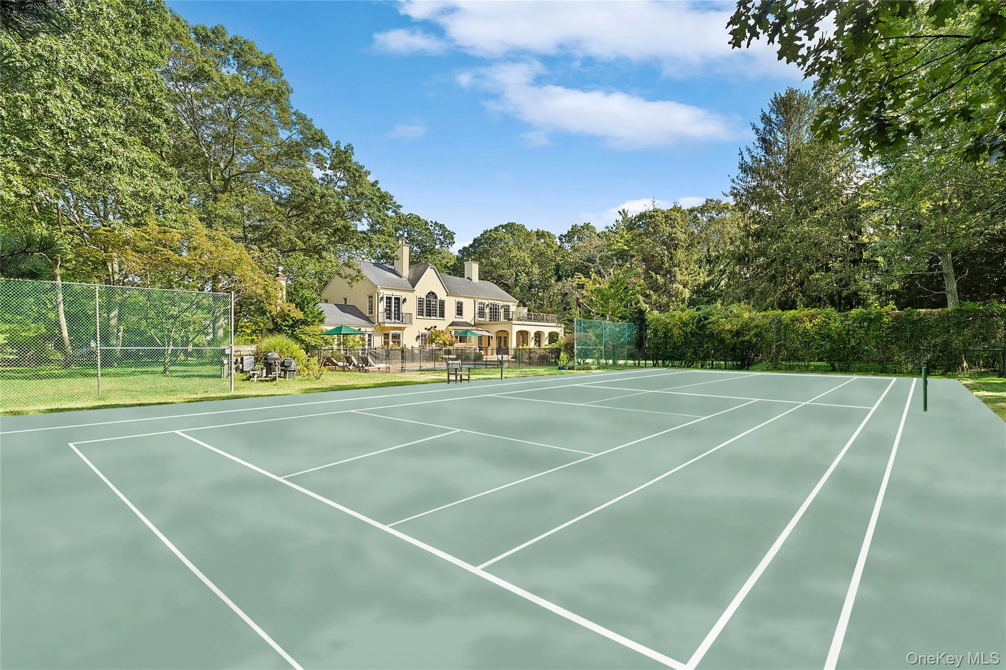 View of tennis court featuring community basketball court and view of scattered trees View of tennis court featuring community basketball court and view of scattered trees