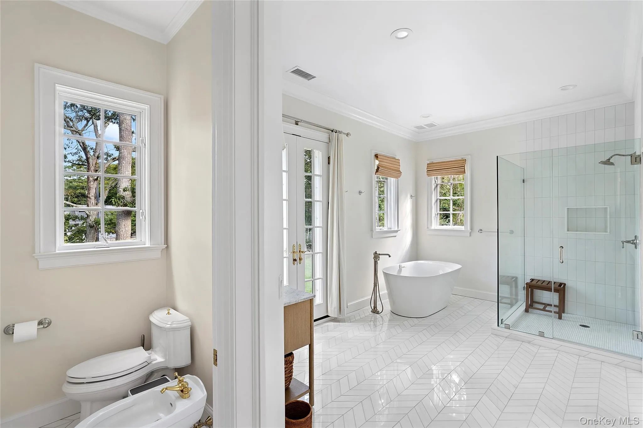 Full bath featuring ornamental molding, light tile patterned floors, a freestanding bath, a stall shower, and a bidet Full bath featuring ornamental molding, light tile patterned floors, a freestanding bath, a stall shower, and a bidet