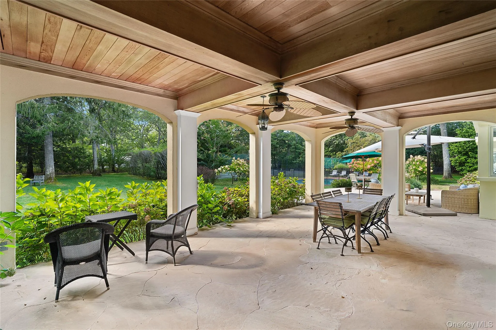 View of patio featuring outdoor dining space, a ceiling fan, and view of wooded area View of patio featuring outdoor dining space, a ceiling fan, and view of wooded area