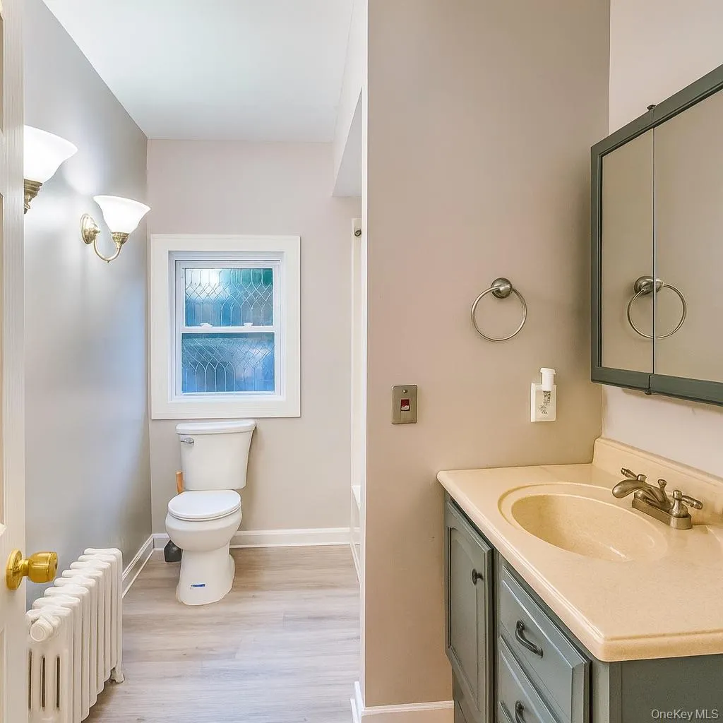 Full bath with radiator, vanity, light wood-style floors, and shower / tub combination Full bath with radiator, vanity, light wood-style floors, and shower / tub combination
