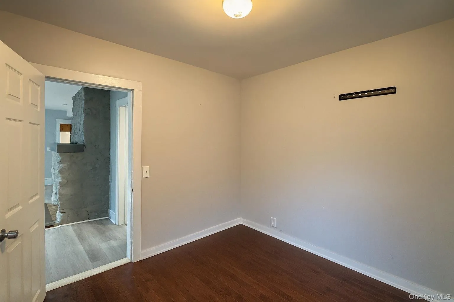 Spare room featuring dark wood-style flooring and baseboards Spare room featuring dark wood-style flooring and baseboards