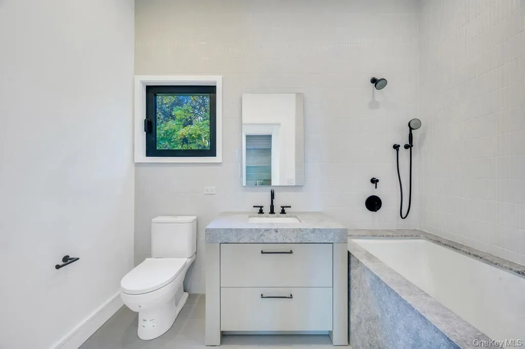 Bathroom featuring vanity, tile walls, and tiled shower / bath combo Bathroom featuring vanity, tile walls, and tiled shower / bath combo