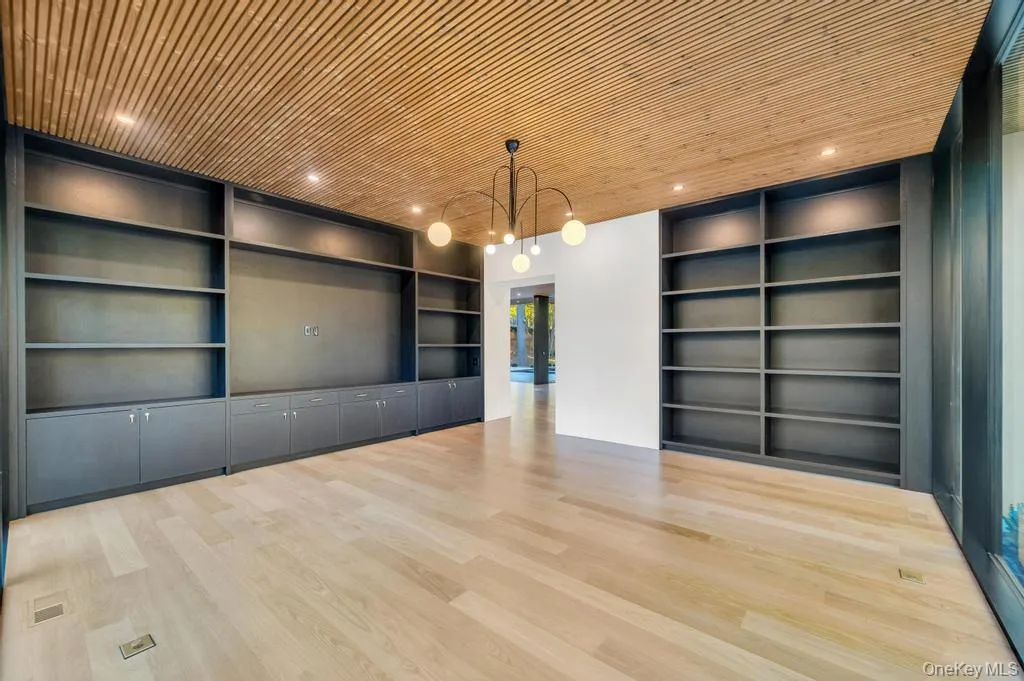 Unfurnished room with built in shelves, light wood-style flooring, wooden ceiling, french doors, and a chandelier Unfurnished room with built in shelves, light wood-style flooring, wooden ceiling, french doors, and a chandelier