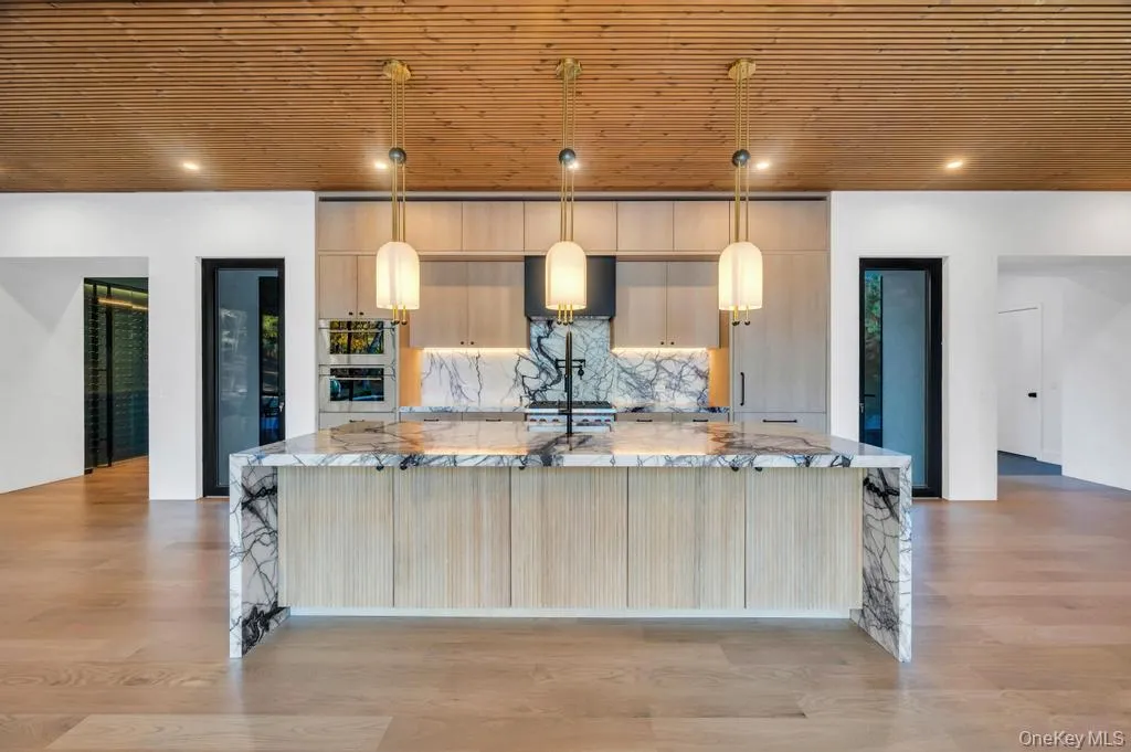 Kitchen featuring light stone counters, decorative backsplash, a large island, modern cabinets, and wooden ceiling Kitchen featuring light stone counters, decorative backsplash, a large island, modern cabinets, and wooden ceiling