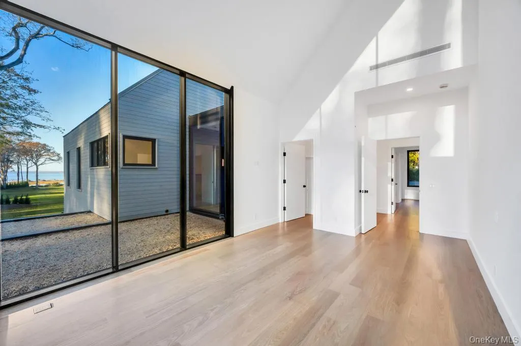 Empty room with wood finished floors, a high ceiling, and a water view Empty room with wood finished floors, a high ceiling, and a water view