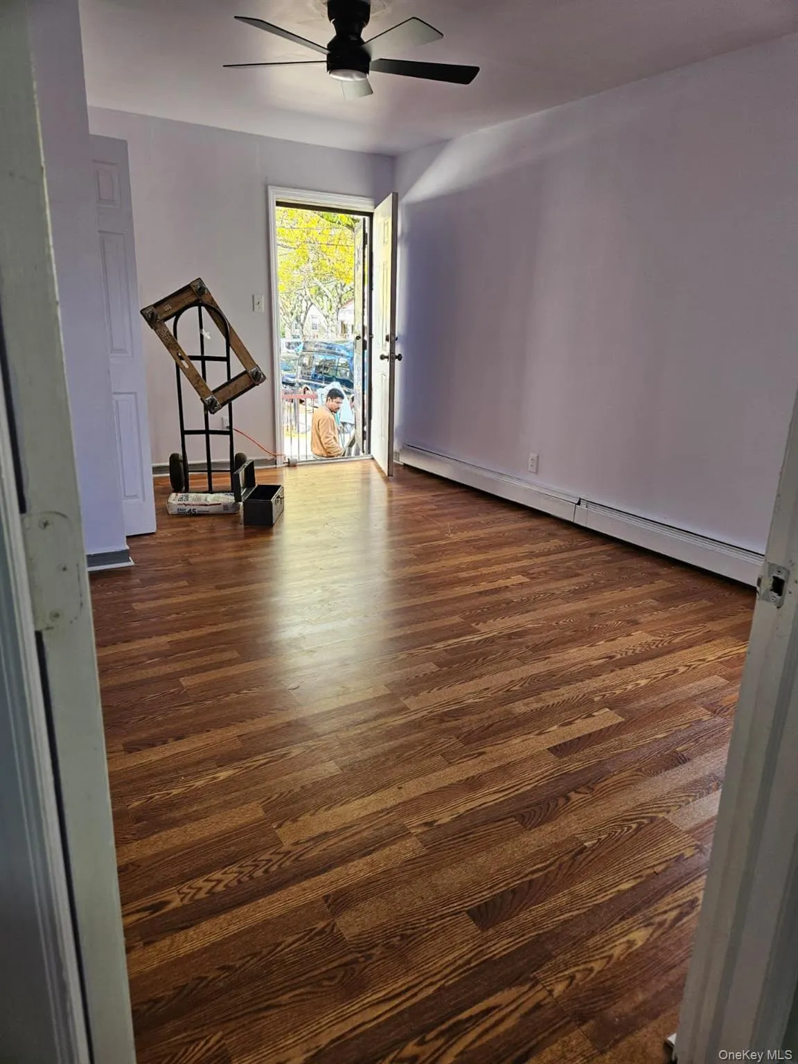 Unfurnished room featuring dark wood-type flooring, a baseboard heating unit, and ceiling fan Unfurnished room featuring dark wood-type flooring, a baseboard heating unit, and ceiling fan
