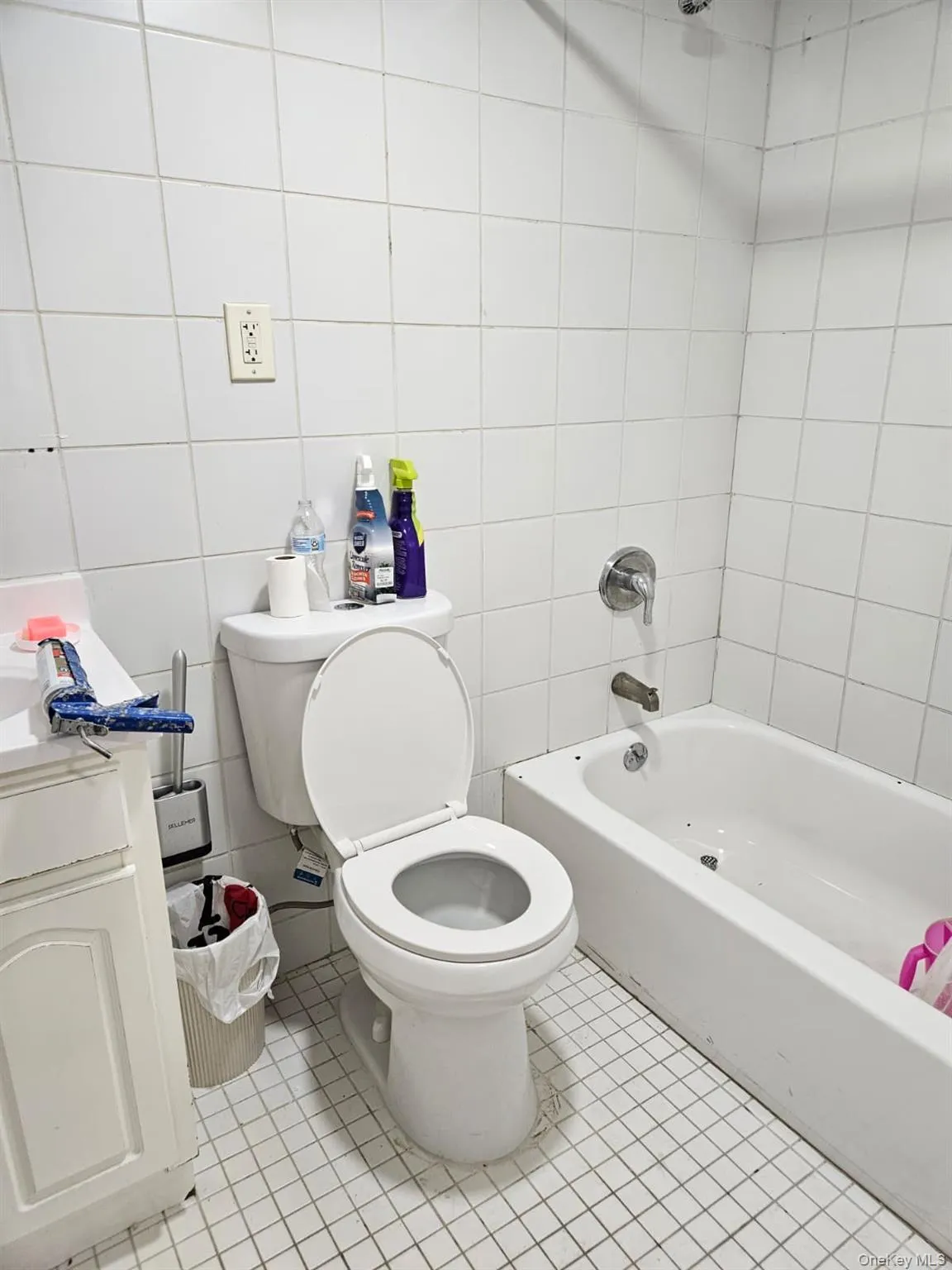 Full bath featuring bathing tub / shower combination, vanity, light tile patterned floors, and tile walls Full bath featuring bathing tub / shower combination, vanity, light tile patterned floors, and tile walls