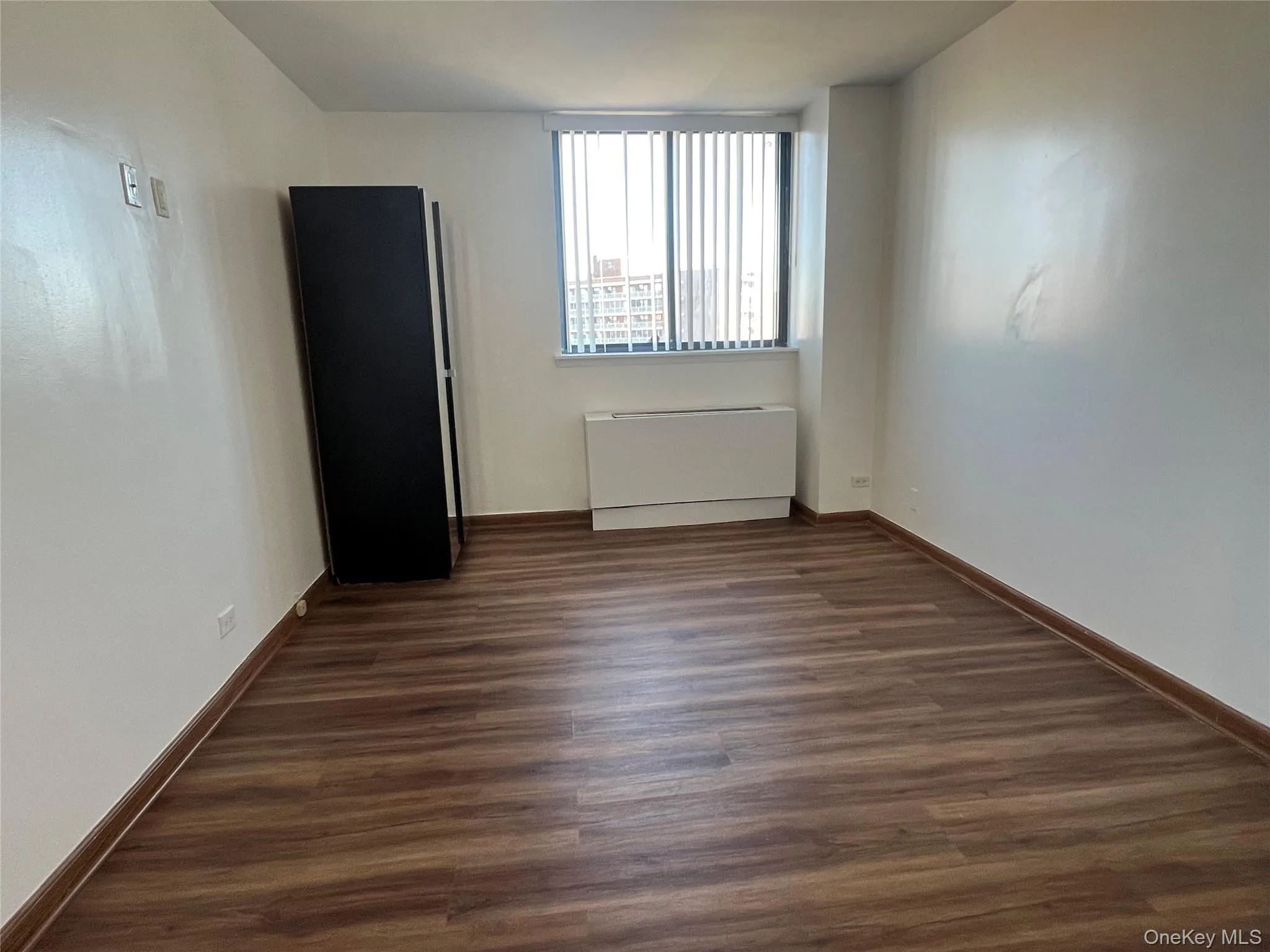 Spare room featuring dark wood-style flooring and radiator Spare room featuring dark wood-style flooring and radiator