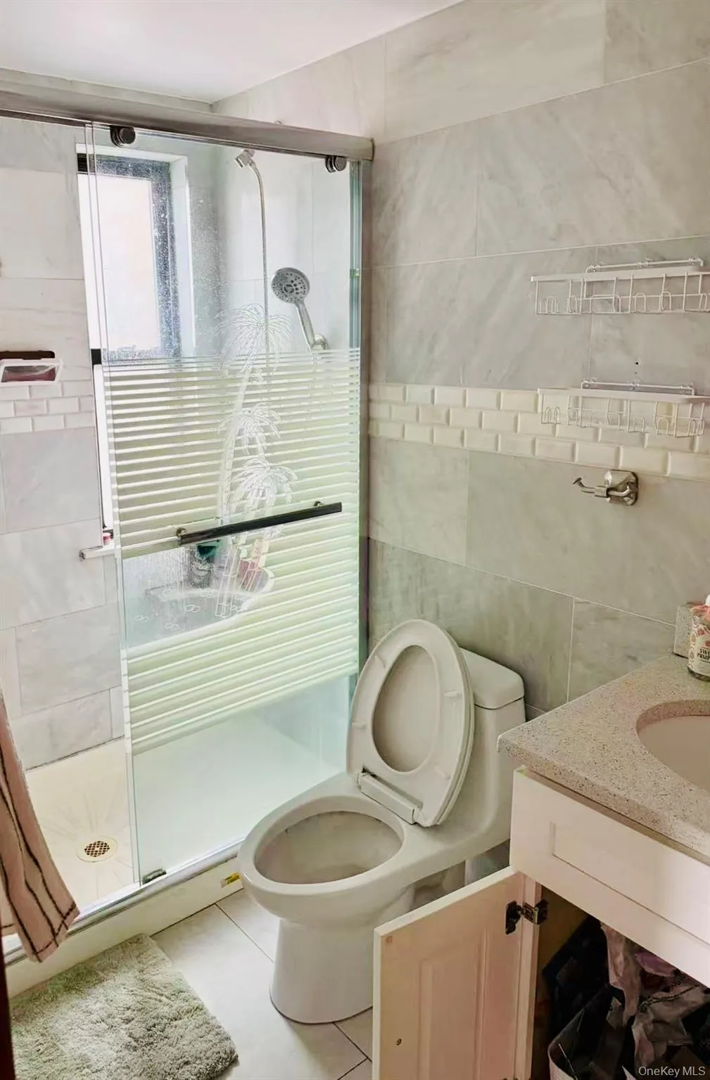 Full bath featuring tile walls, vanity, light tile patterned floors, and a stall shower Full bath featuring tile walls, vanity, light tile patterned floors, and a stall shower