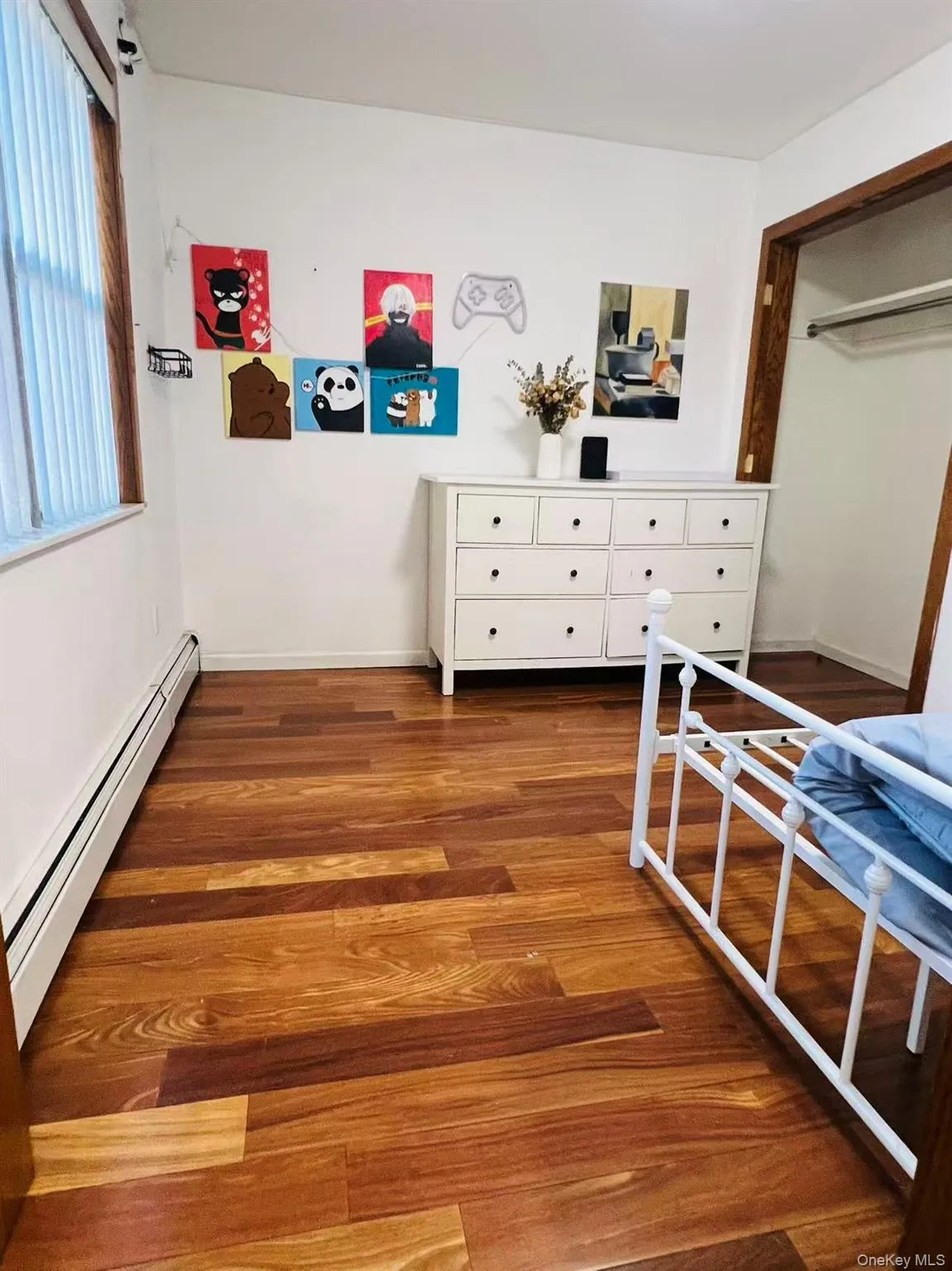 Bedroom with baseboard heating, dark wood-type flooring, and a closet Bedroom with baseboard heating, dark wood-type flooring, and a closet
