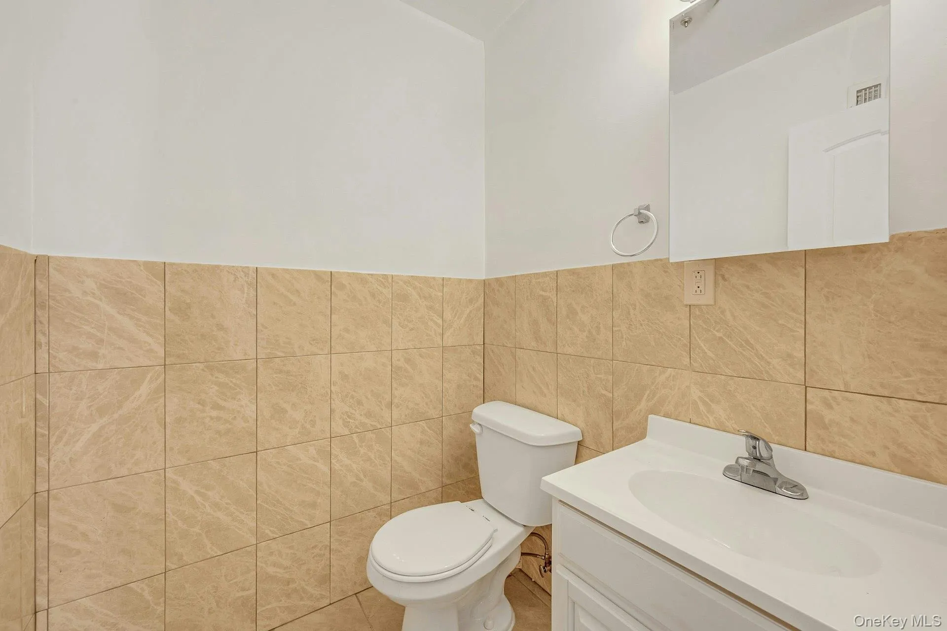 Half bathroom featuring vanity and tile walls Half bathroom featuring vanity and tile walls