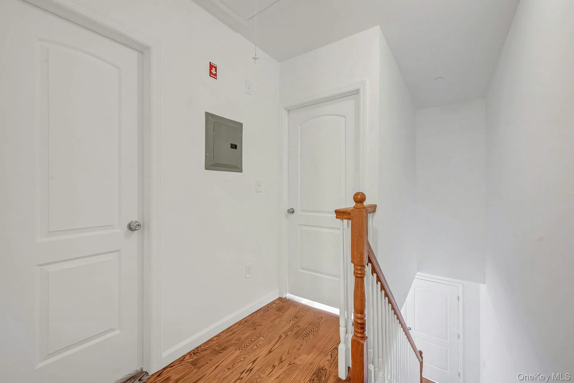 Second floor hallway featuring attic access and upstairs landing wood finished floors and electric panel Second floor hallway featuring attic access and upstairs landing wood finished floors and electric panel