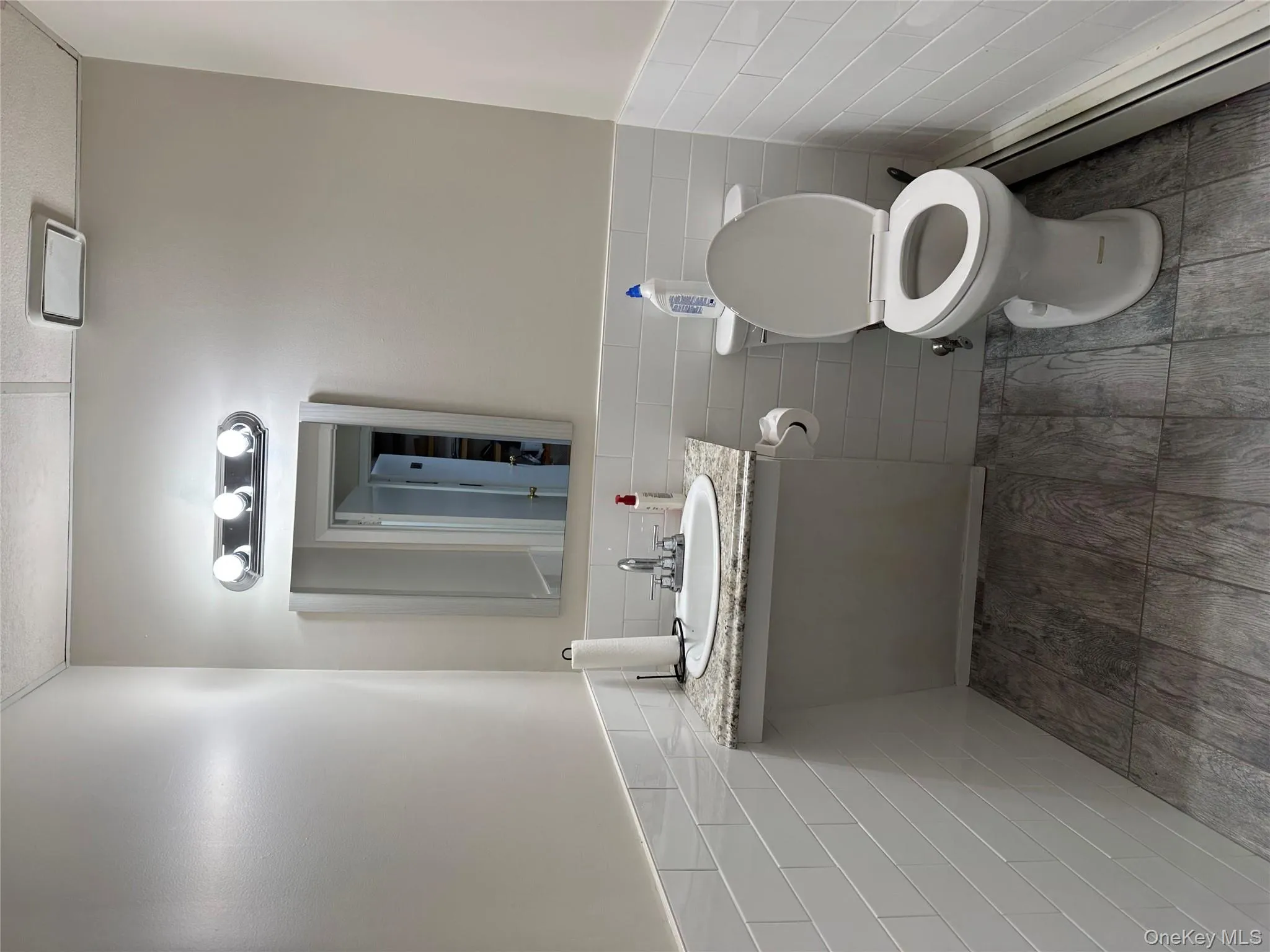 Bathroom with tile walls, wainscoting, baseboard heating, vanity, and wood finished floors Bathroom with tile walls, wainscoting, baseboard heating, vanity, and wood finished floors