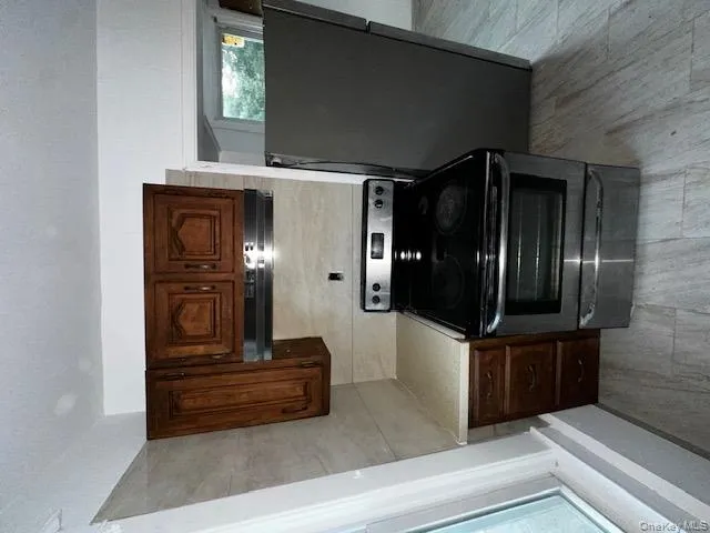 Kitchen featuring light countertops, stove, stainless steel fridge, range hood, and light wood-style floors Kitchen featuring light countertops, stove, stainless steel fridge, range hood, and light wood-style floors