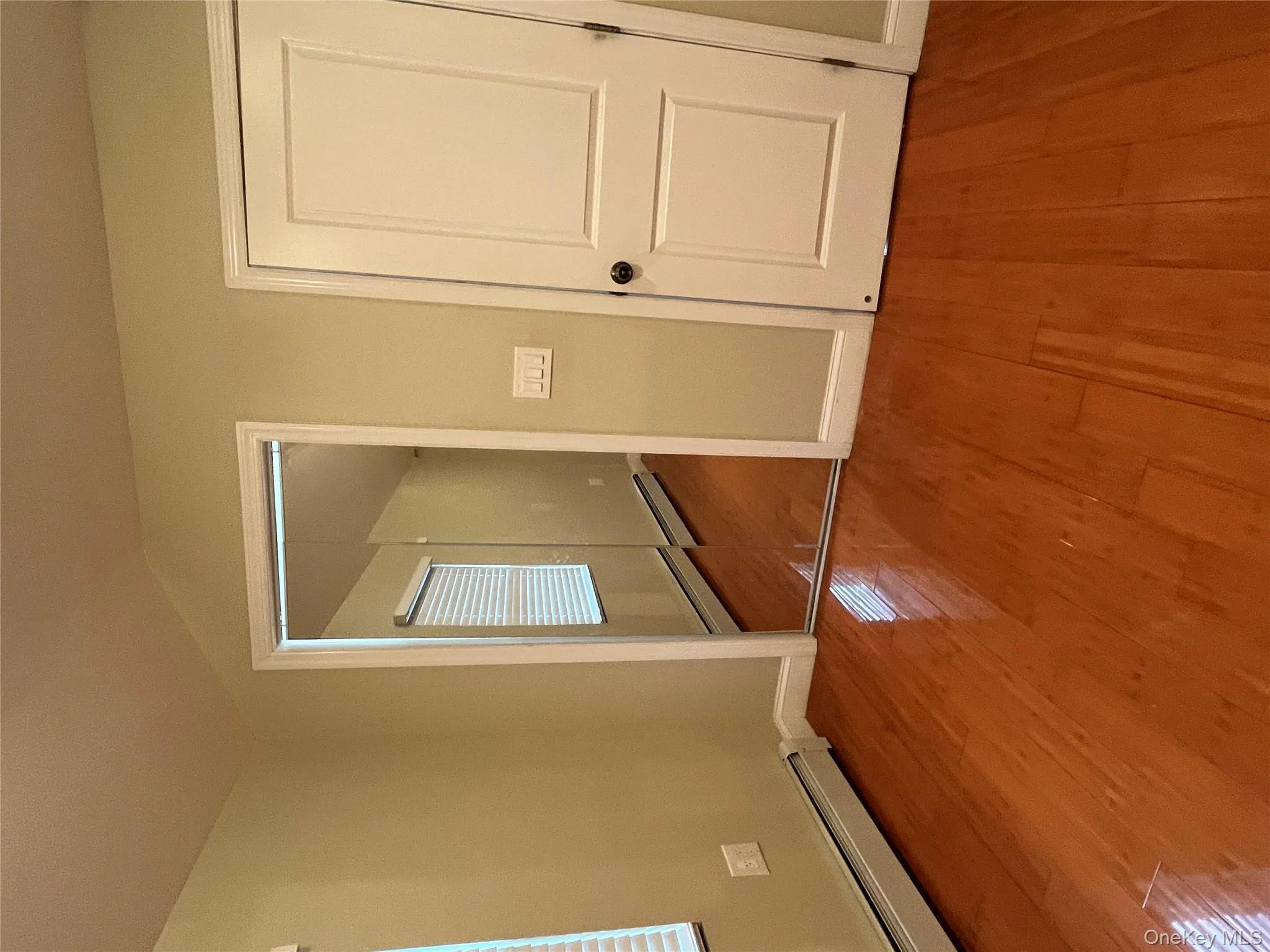 Unfurnished bedroom with a baseboard heating unit, wood finished floors, a closet, and lofted ceiling Unfurnished bedroom with a baseboard heating unit, wood finished floors, a closet, and lofted ceiling