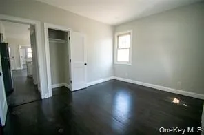 Unfurnished bedroom featuring a closet, freestanding refrigerator, and dark wood-style flooring Unfurnished bedroom featuring a closet, freestanding refrigerator, and dark wood-style flooring