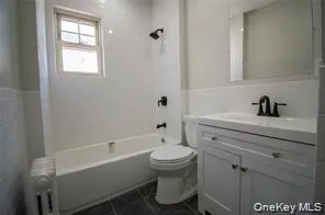 Full bathroom featuring vanity, radiator, shower / tub combination, and dark tile patterned flooring Full bathroom featuring vanity, radiator, shower / tub combination, and dark tile patterned flooring