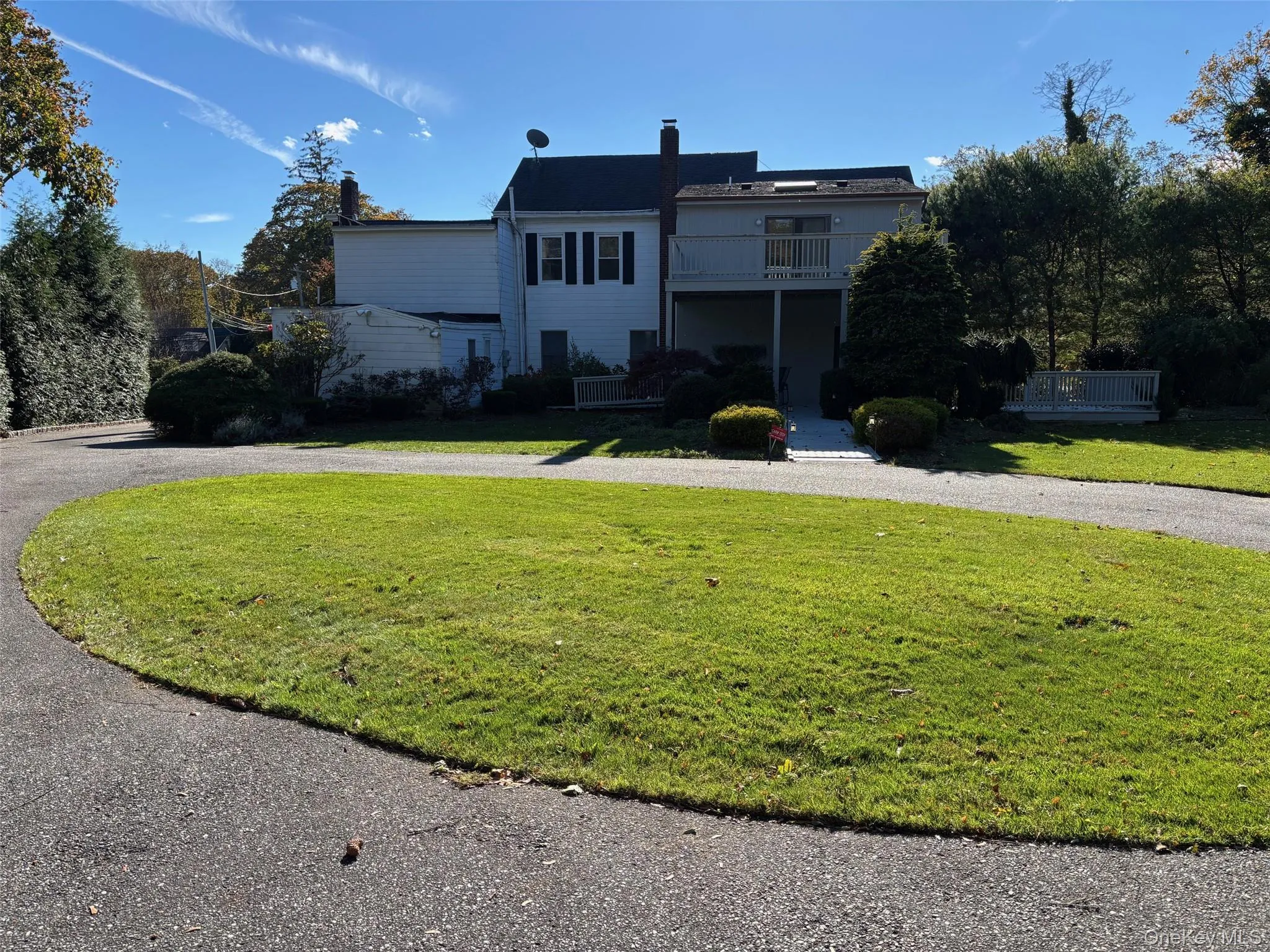 View of front of property featuring a chimney, a front lawn, and a balcony View of front of property featuring a chimney, a front lawn, and a balcony