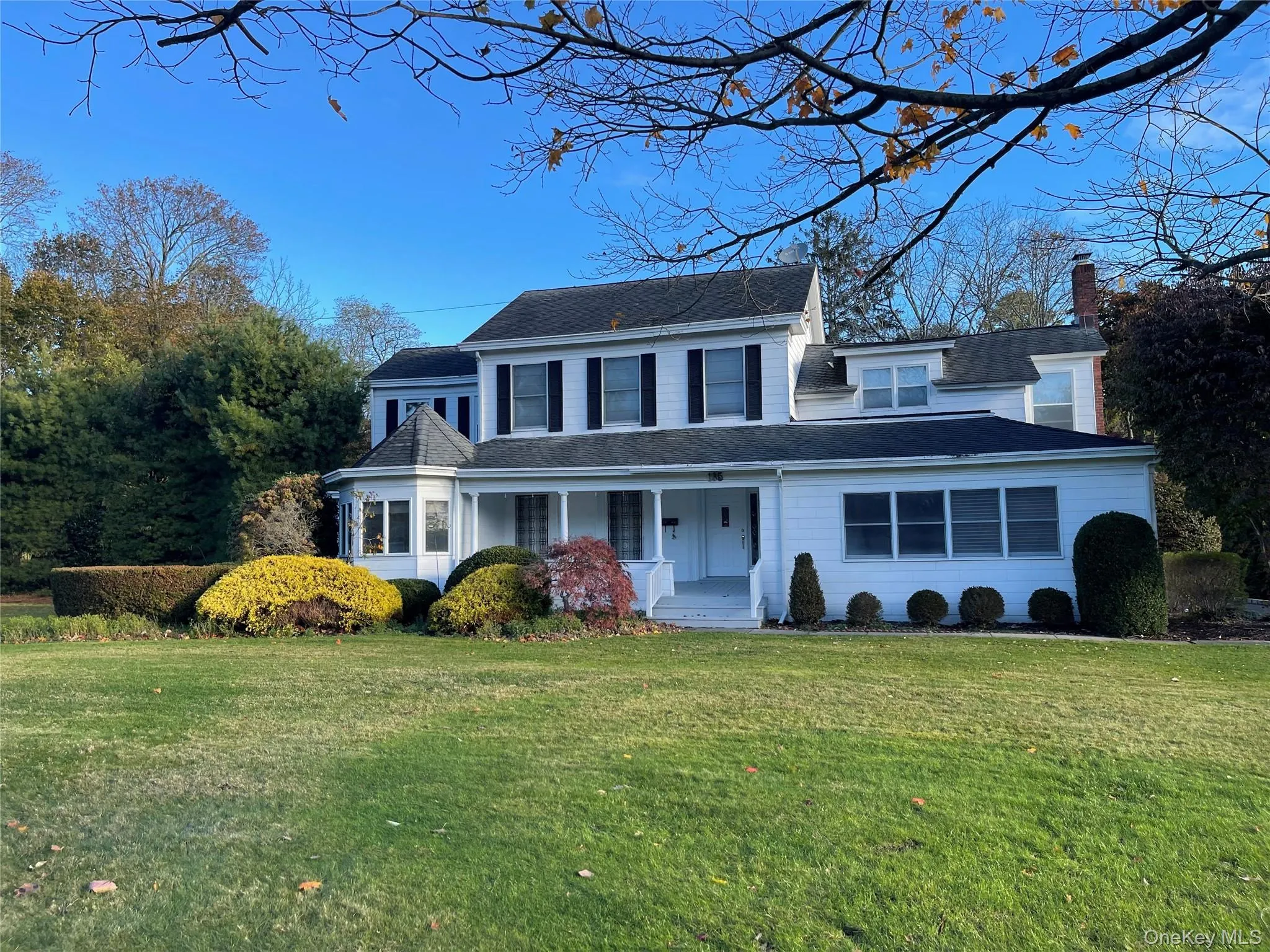 Traditional-style home featuring a porch, a front lawn, a chimney, and a shingled roof Traditional-style home featuring a porch, a front lawn, a chimney, and a shingled roof