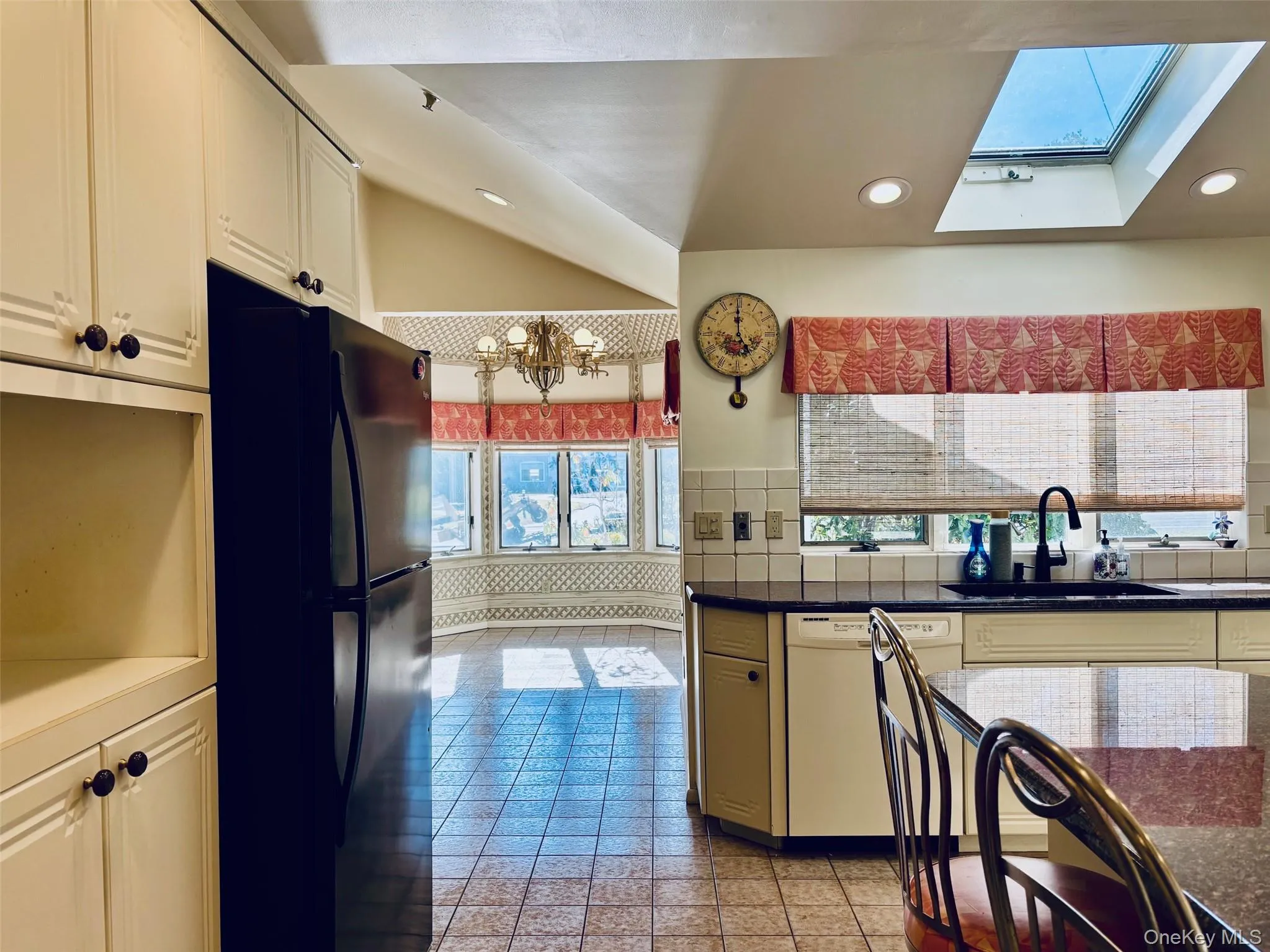 Kitchen with dishwasher, freestanding refrigerator, a skylight, recessed lighting, and dark countertops Kitchen with dishwasher, freestanding refrigerator, a skylight, recessed lighting, and dark countertops