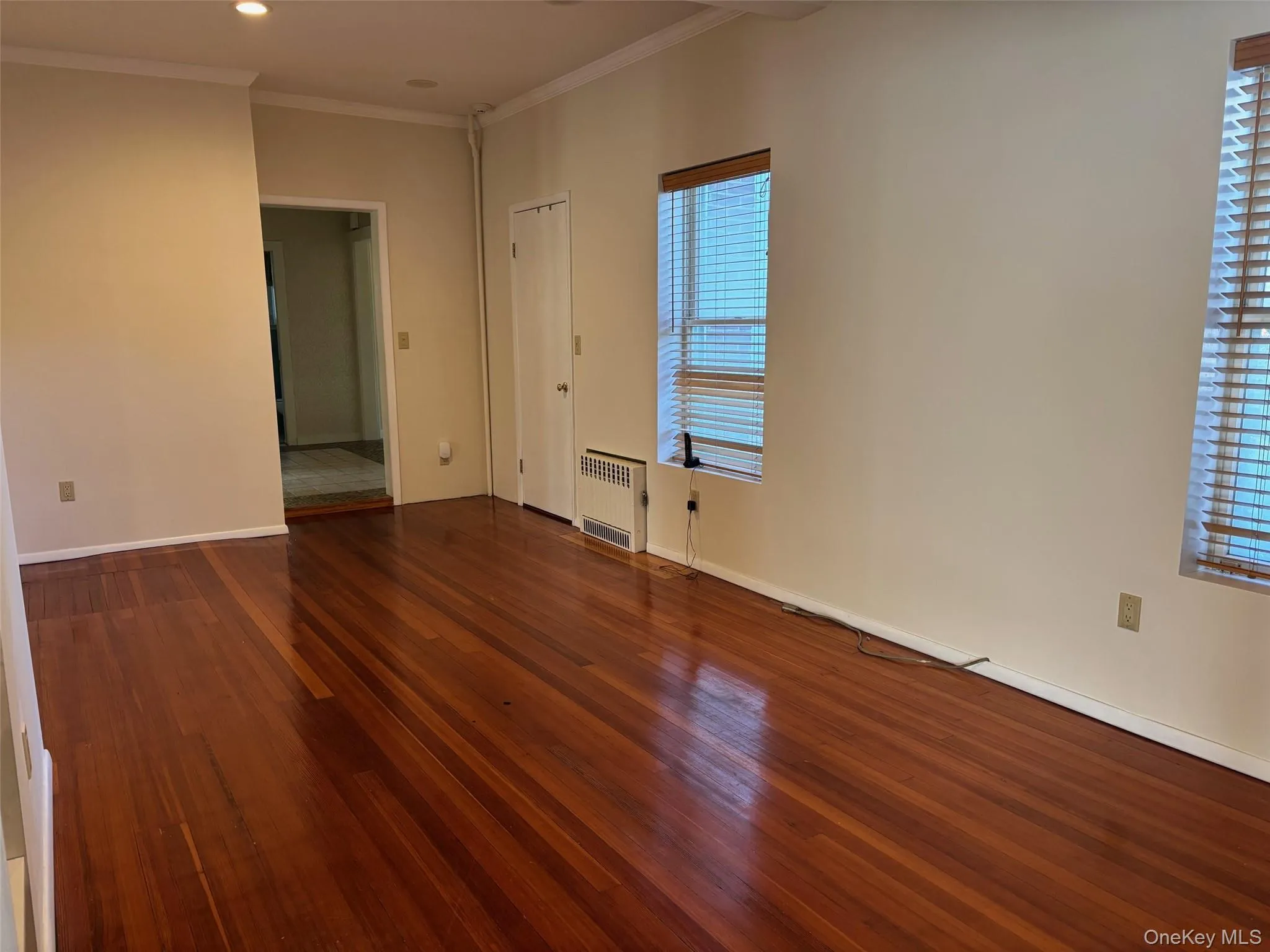 Spare room featuring ornamental molding, dark wood-type flooring, radiator heating unit, and recessed lighting Spare room featuring ornamental molding, dark wood-type flooring, radiator heating unit, and recessed lighting