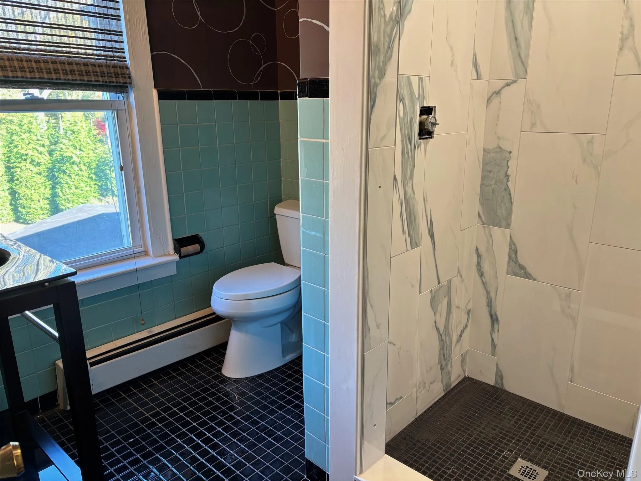 Bathroom featuring tile patterned floors, tile walls, a baseboard heating unit, and tiled shower Bathroom featuring tile patterned floors, tile walls, a baseboard heating unit, and tiled shower