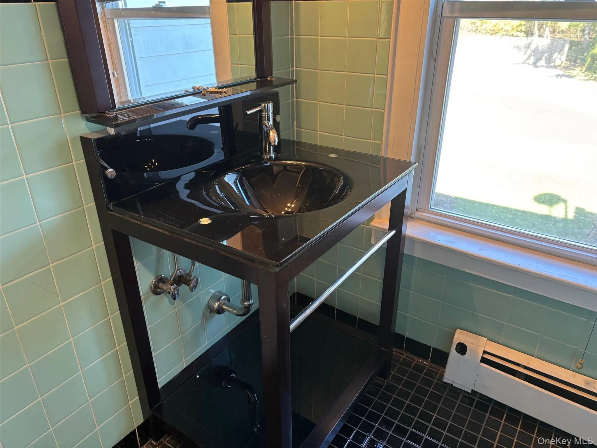 Bathroom featuring tile walls, a baseboard heating unit, plenty of natural light, and dark tile patterned floors Bathroom featuring tile walls, a baseboard heating unit, plenty of natural light, and dark tile patterned floors