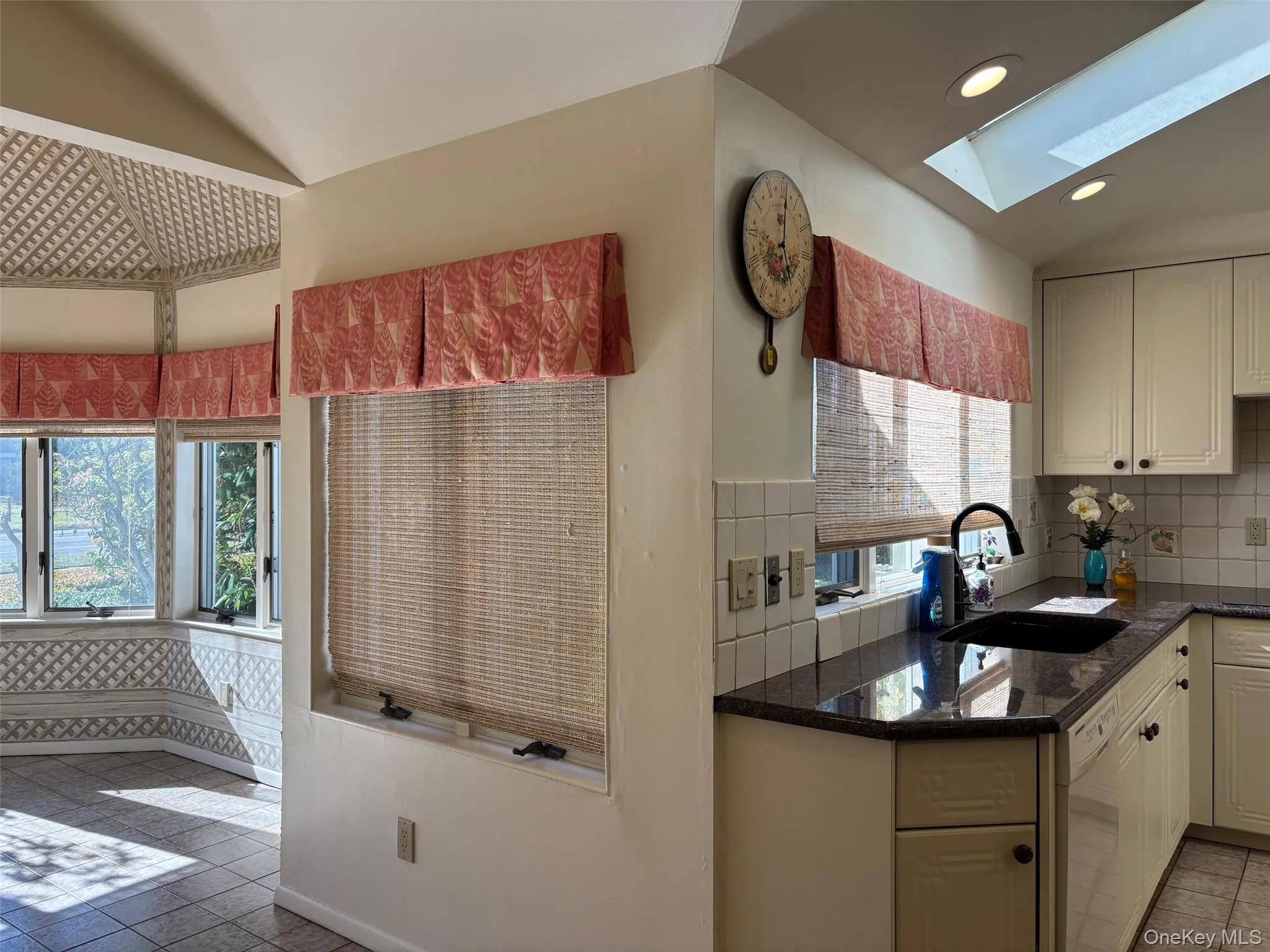 Kitchen featuring light tile patterned floors, dark stone counters, decorative backsplash, recessed lighting, and a skylight Kitchen featuring light tile patterned floors, dark stone counters, decorative backsplash, recessed lighting, and a skylight