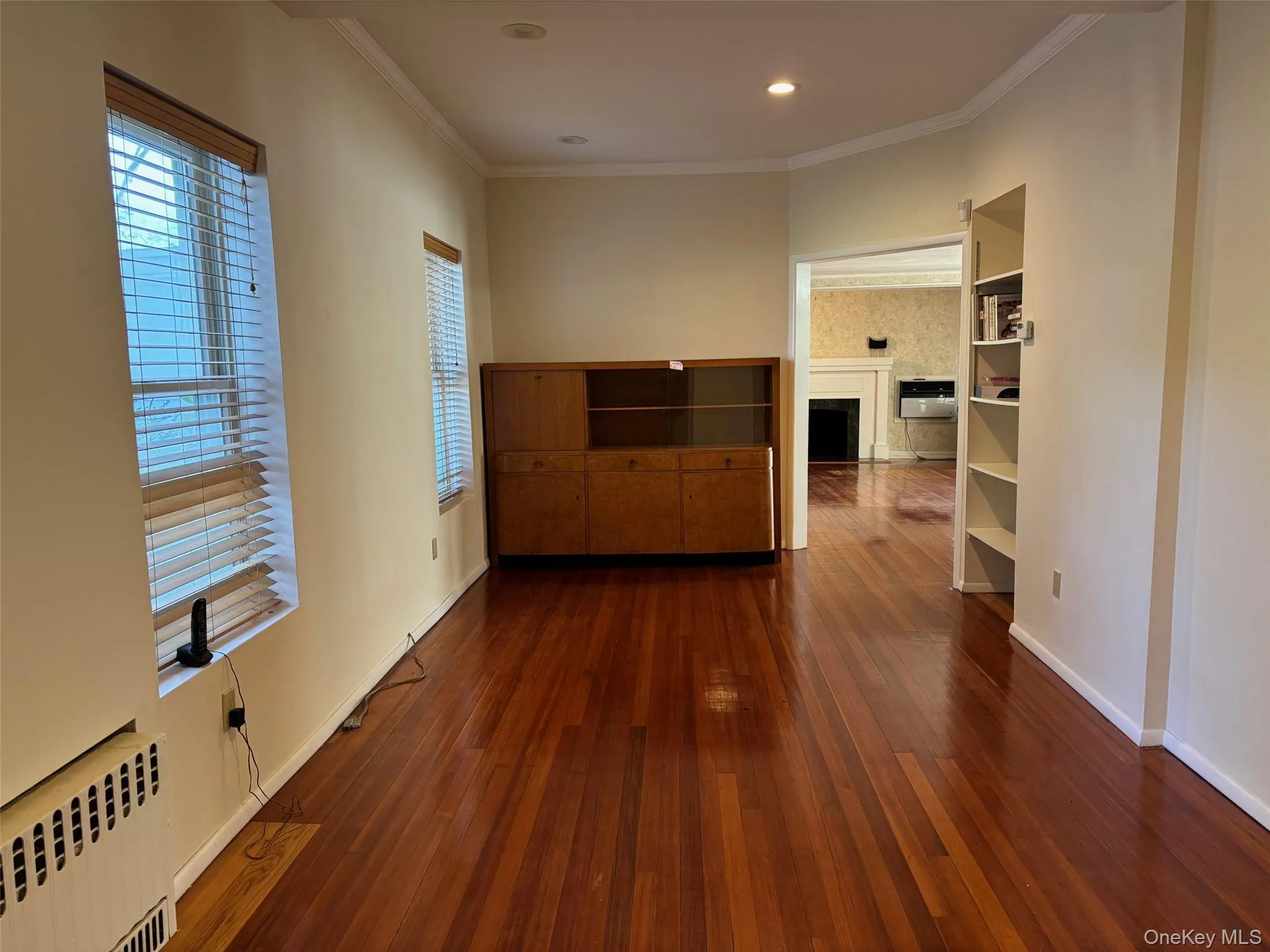 Spare room with crown molding, a fireplace, radiator heating unit, dark wood finished floors, and recessed lighting Spare room with crown molding, a fireplace, radiator heating unit, dark wood finished floors, and recessed lighting
