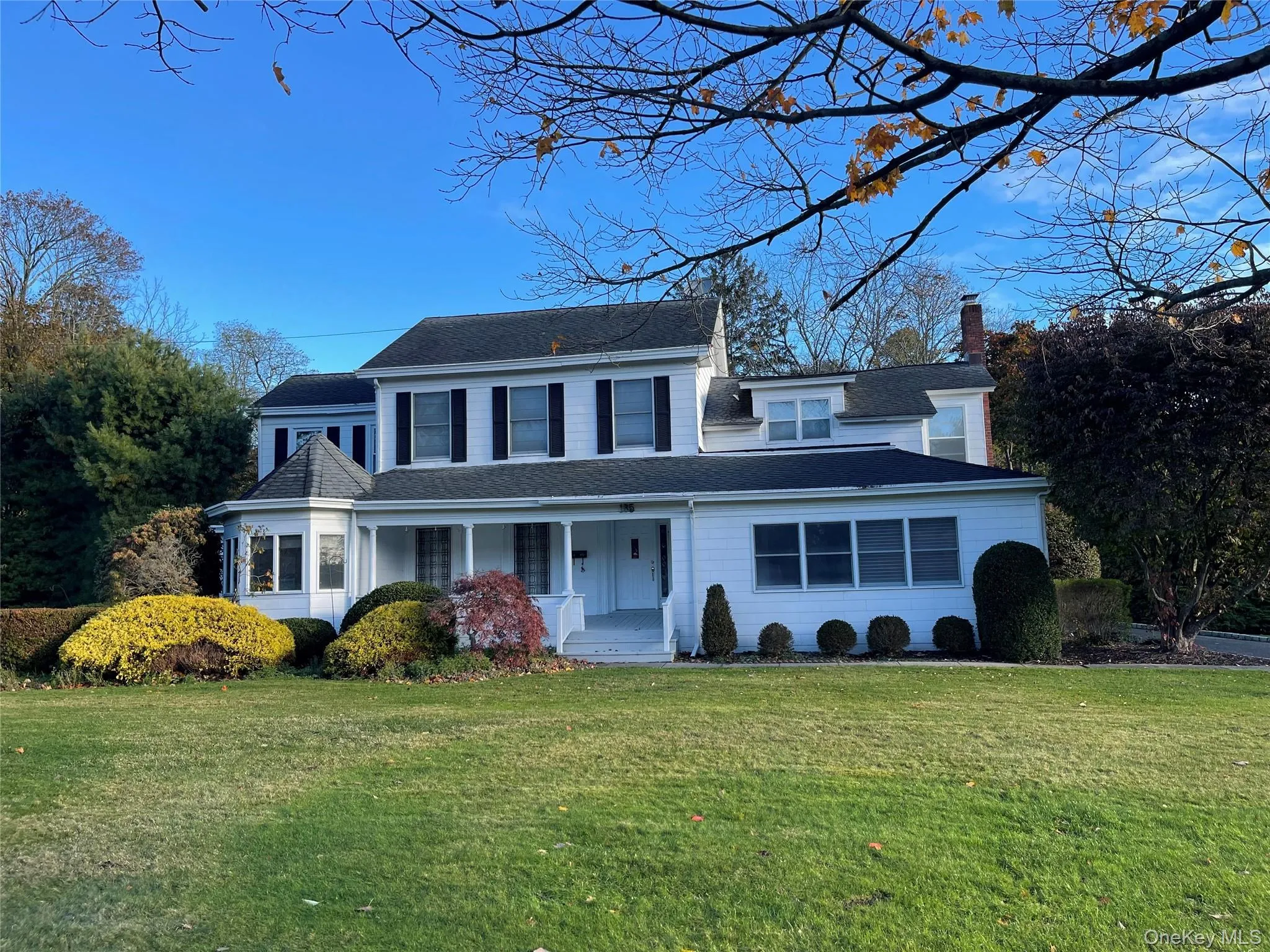 View of front of home featuring a front lawn, covered porch, roof with shingles, and a chimney View of front of home featuring a front lawn, covered porch, roof with shingles, and a chimney