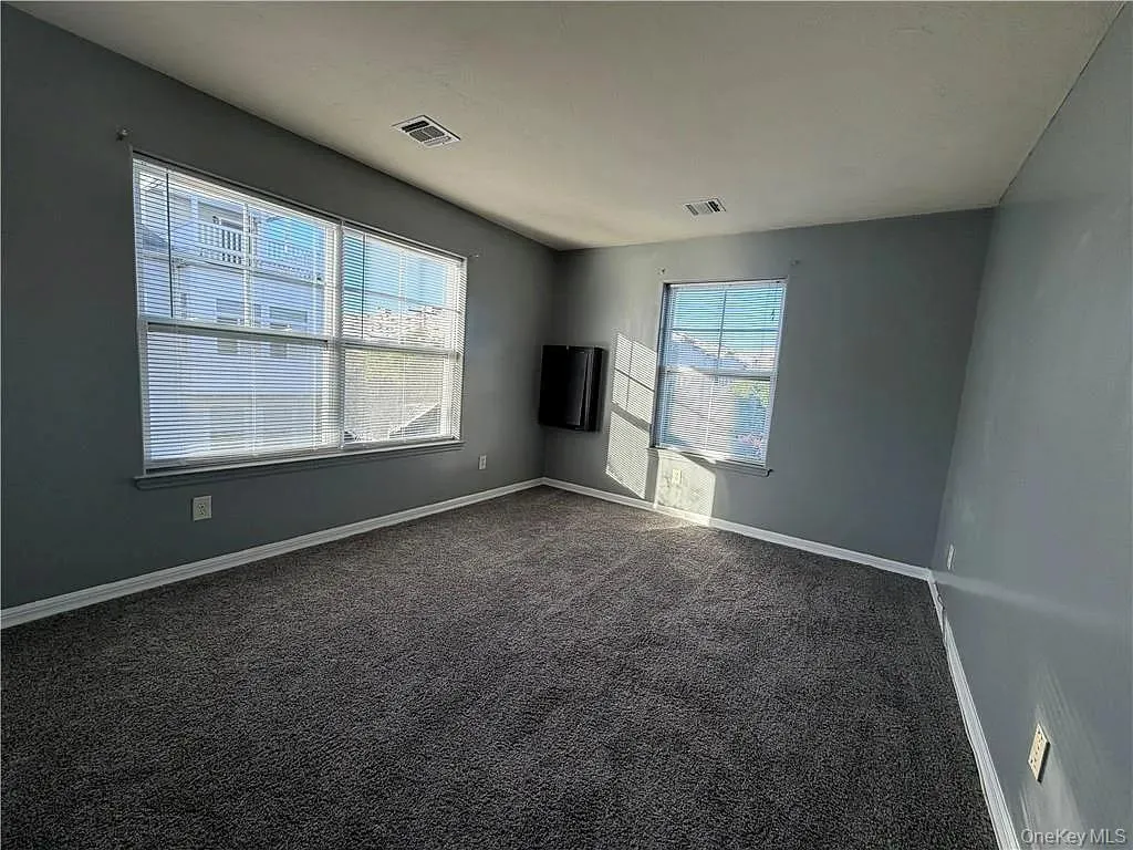 Empty room featuring dark colored carpet and baseboards Empty room featuring dark colored carpet and baseboards