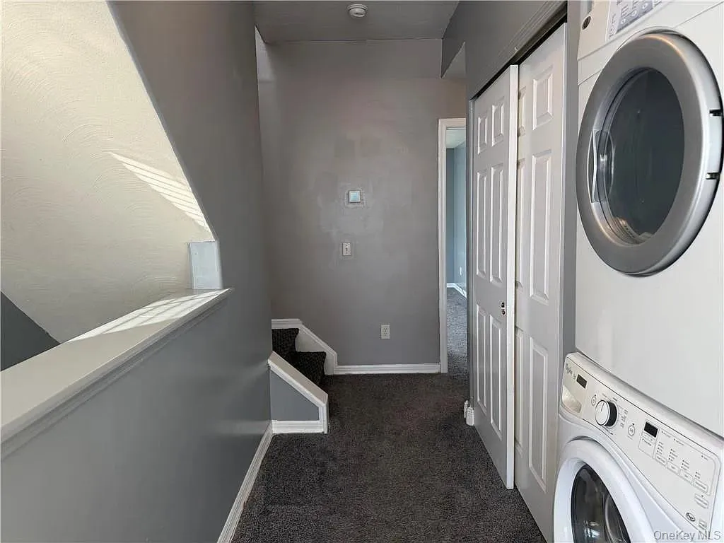 Laundry room with dark carpet and stacked washer / dryer Laundry room with dark carpet and stacked washer / dryer