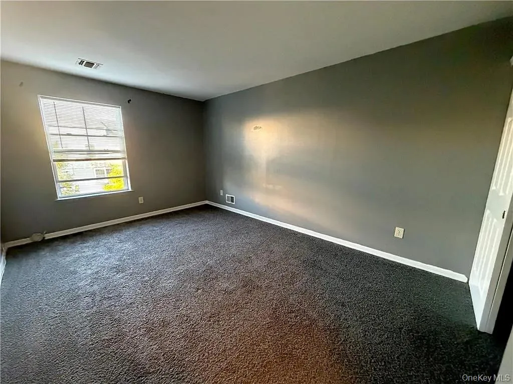 Spare room featuring dark colored carpet and baseboards Spare room featuring dark colored carpet and baseboards
