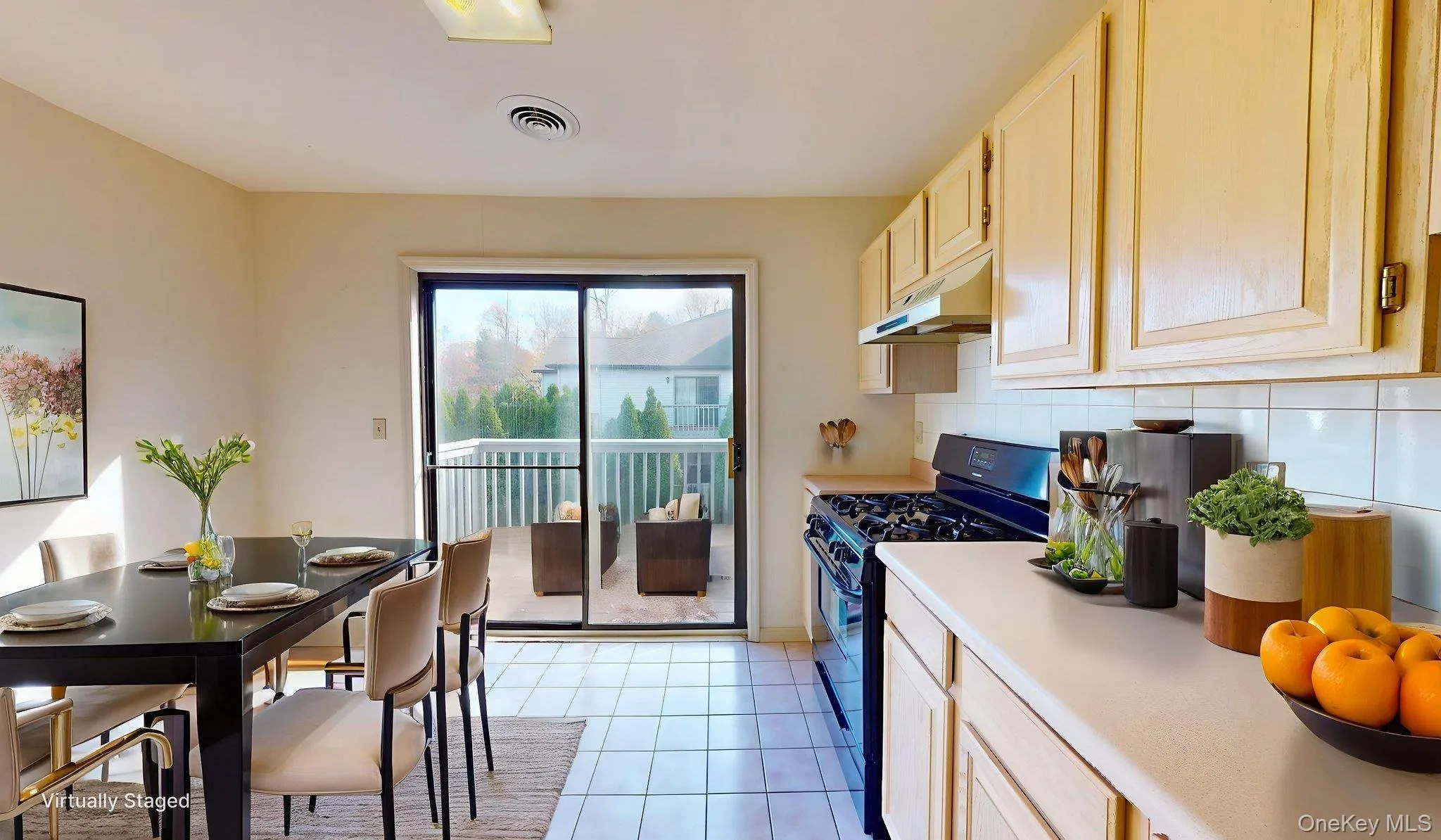Kitchen with black gas range, light brown cabinetry, light countertops, light tile patterned flooring, and under cabinet range hood Kitchen with black gas range, light brown cabinetry, light countertops, light tile patterned flooring, and under cabinet range hood