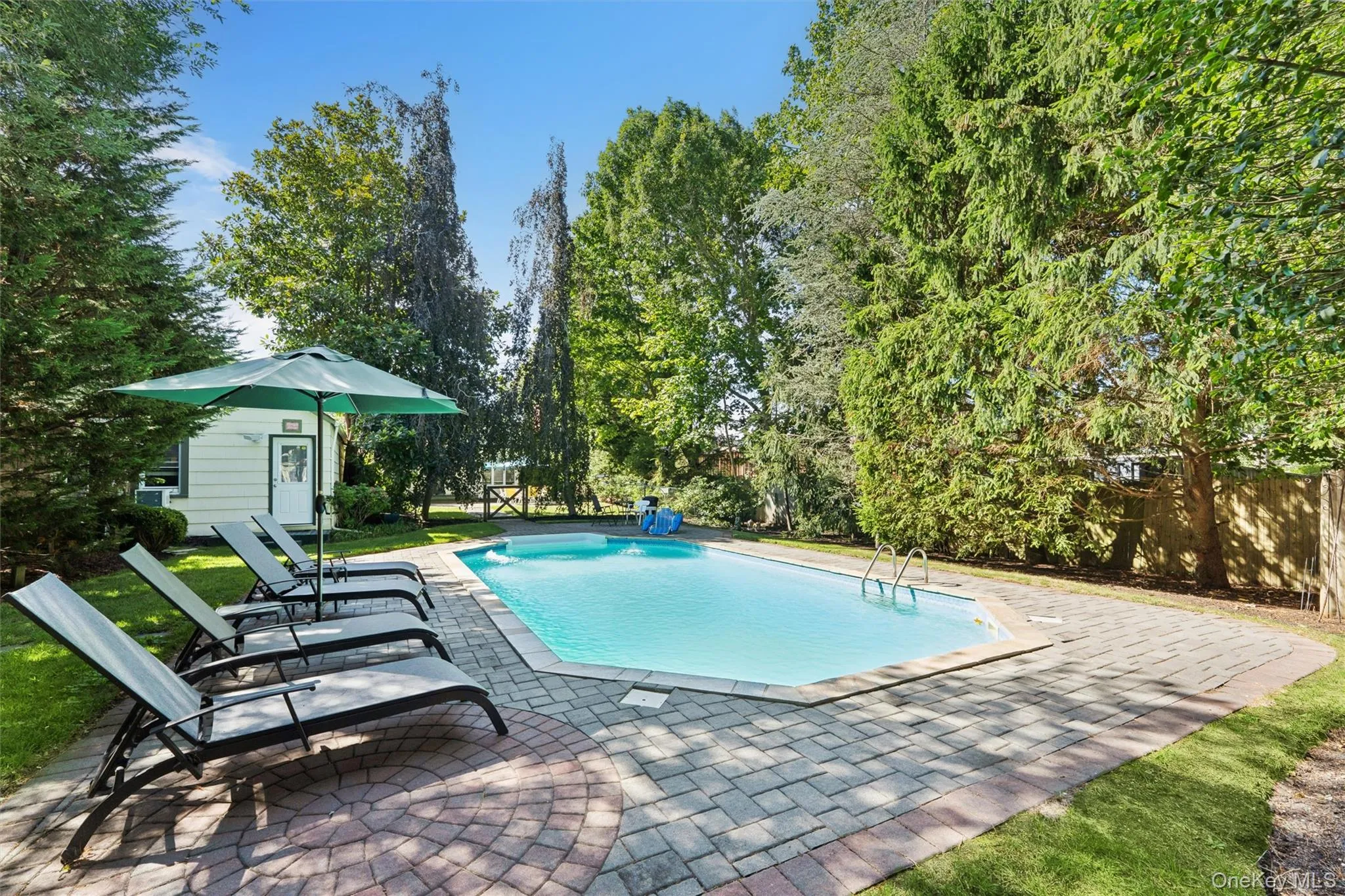 Outdoor pool featuring a patio, an outdoor structure, and view of wooded area Outdoor pool featuring a patio, an outdoor structure, and view of wooded area