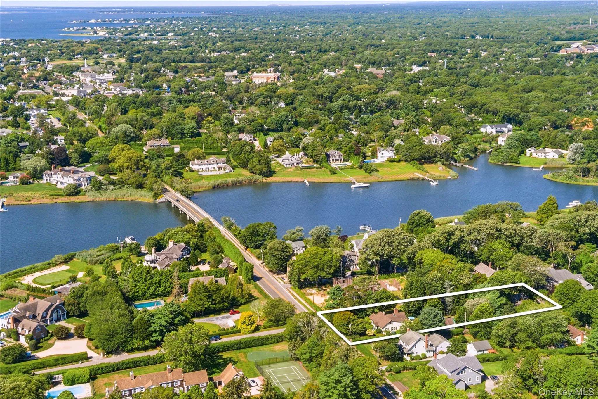Aerial perspective of suburban area featuring a large body of water, property boundaries highlighted, and a notable bridge Aerial perspective of suburban area featuring a large body of water, property boundaries highlighted, and a notable bridge