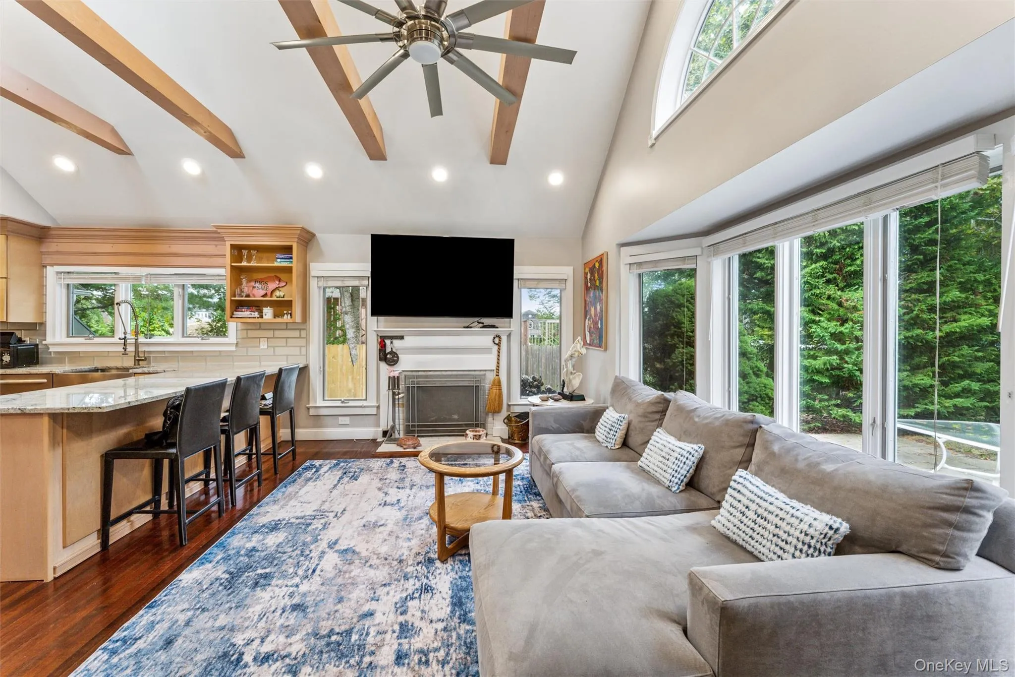 Living room with recessed lighting, high vaulted ceiling, dark wood-style flooring, a fireplace with flush hearth, and ceiling fan Living room with recessed lighting, high vaulted ceiling, dark wood-style flooring, a fireplace with flush hearth, and ceiling fan