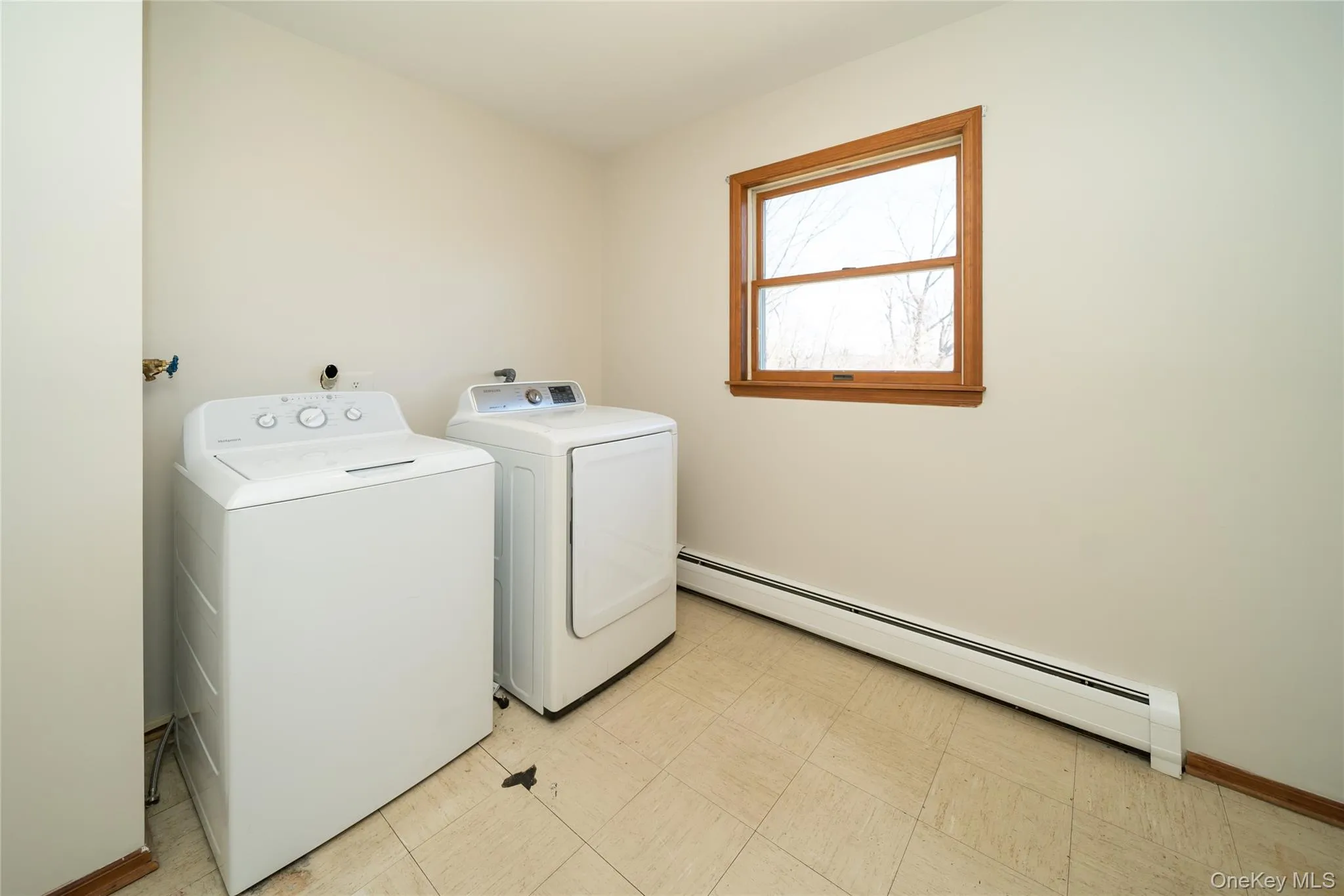 Washroom featuring a baseboard heating unit, washing machine and dryer, and light flooring Washroom featuring a baseboard heating unit, washing machine and dryer, and light flooring