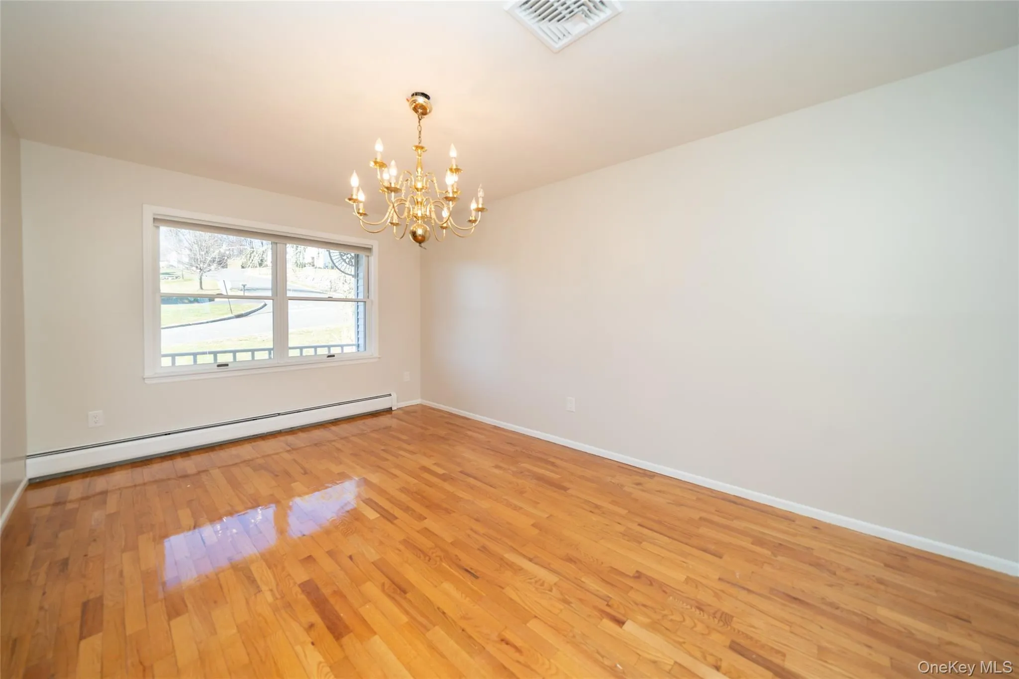 Empty room featuring baseboard heating, a chandelier, and light wood-style flooring Empty room featuring baseboard heating, a chandelier, and light wood-style flooring