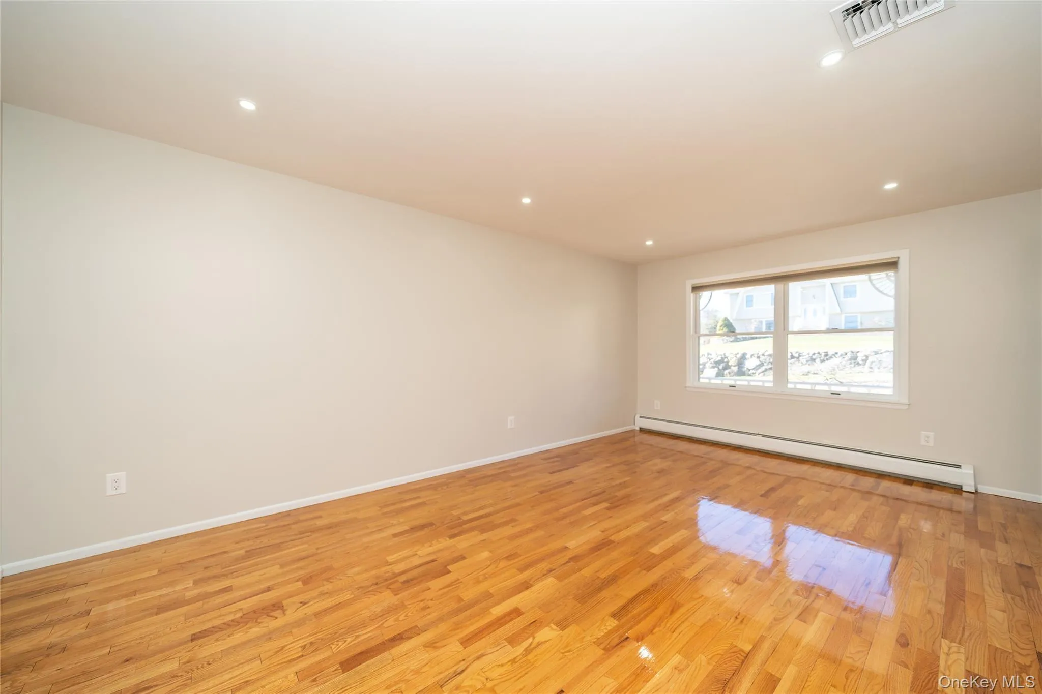 Spare room featuring light wood-style flooring, a baseboard radiator, and recessed lighting Spare room featuring light wood-style flooring, a baseboard radiator, and recessed lighting