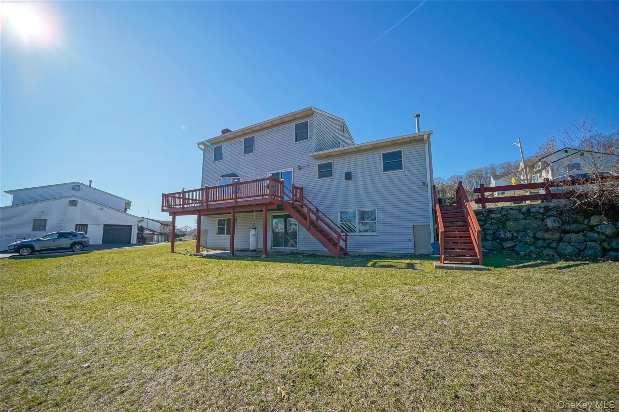Back of house with a deck, stairs, and a lawn Back of house with a deck, stairs, and a lawn