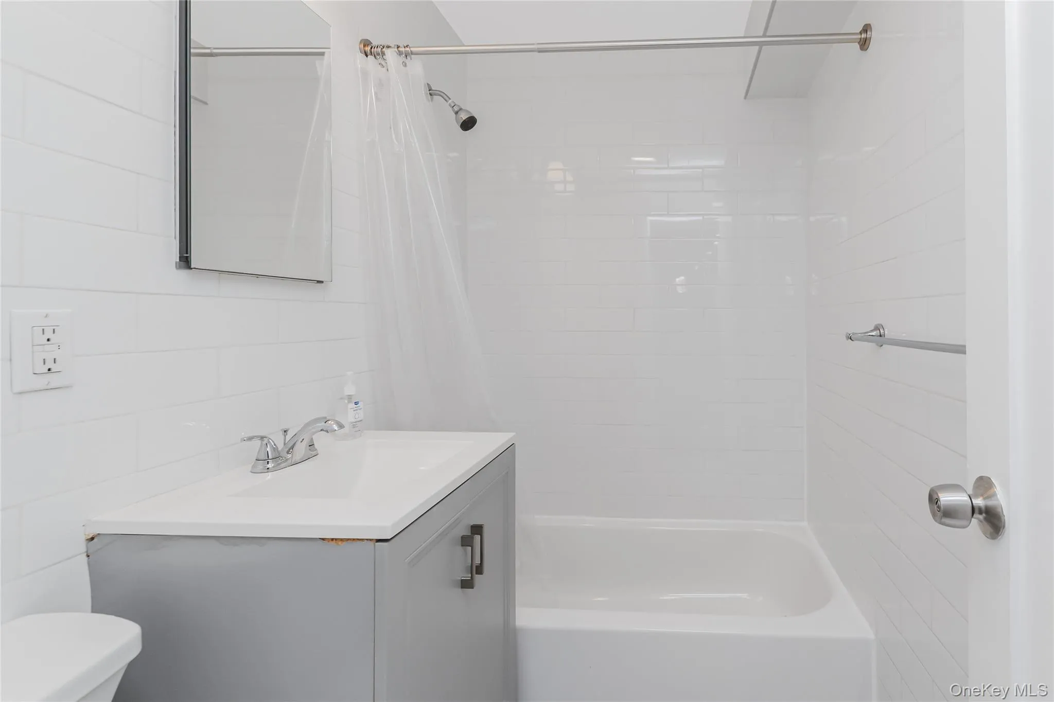 Full bath with vanity, shower / bath combo, and tile walls Full bath with vanity, shower / bath combo, and tile walls