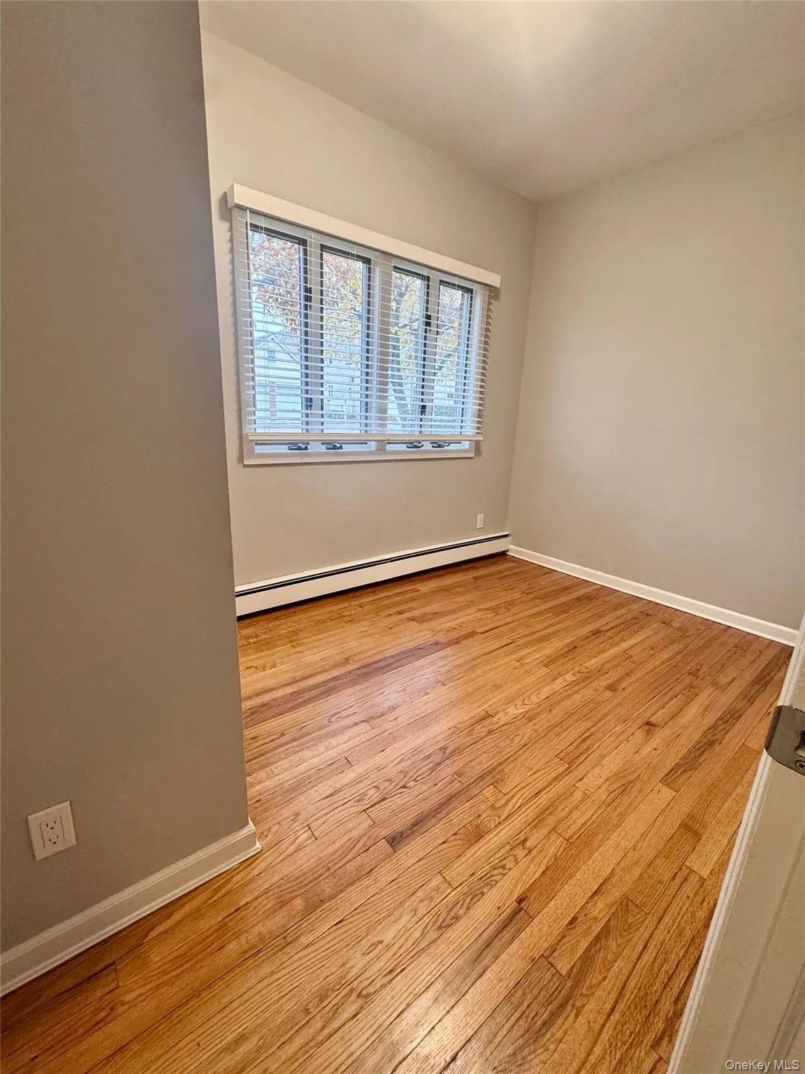 Bedroom 1 with light wood-style flooring and a baseboard heating unit. Bedroom 1 with light wood-style flooring and a baseboard heating unit.