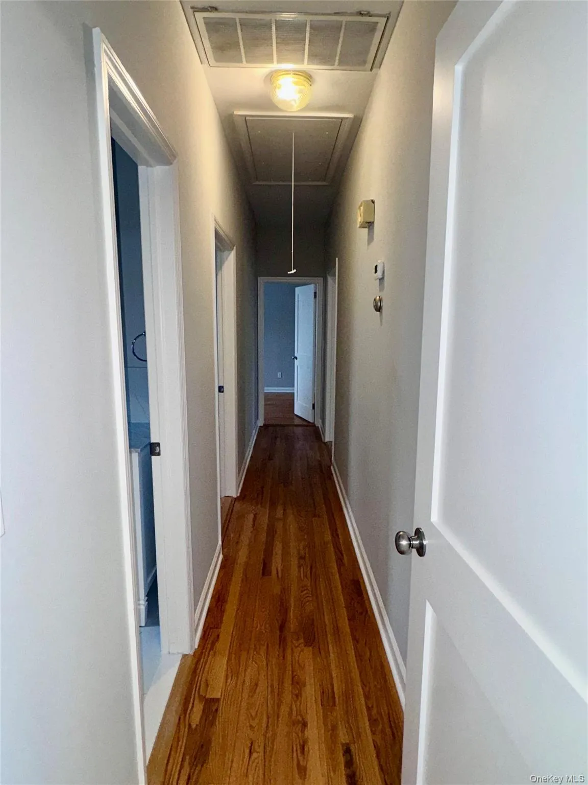 Hall to Bedrooms featuring attic access and wood finished floors Hall to Bedrooms featuring attic access and wood finished floors