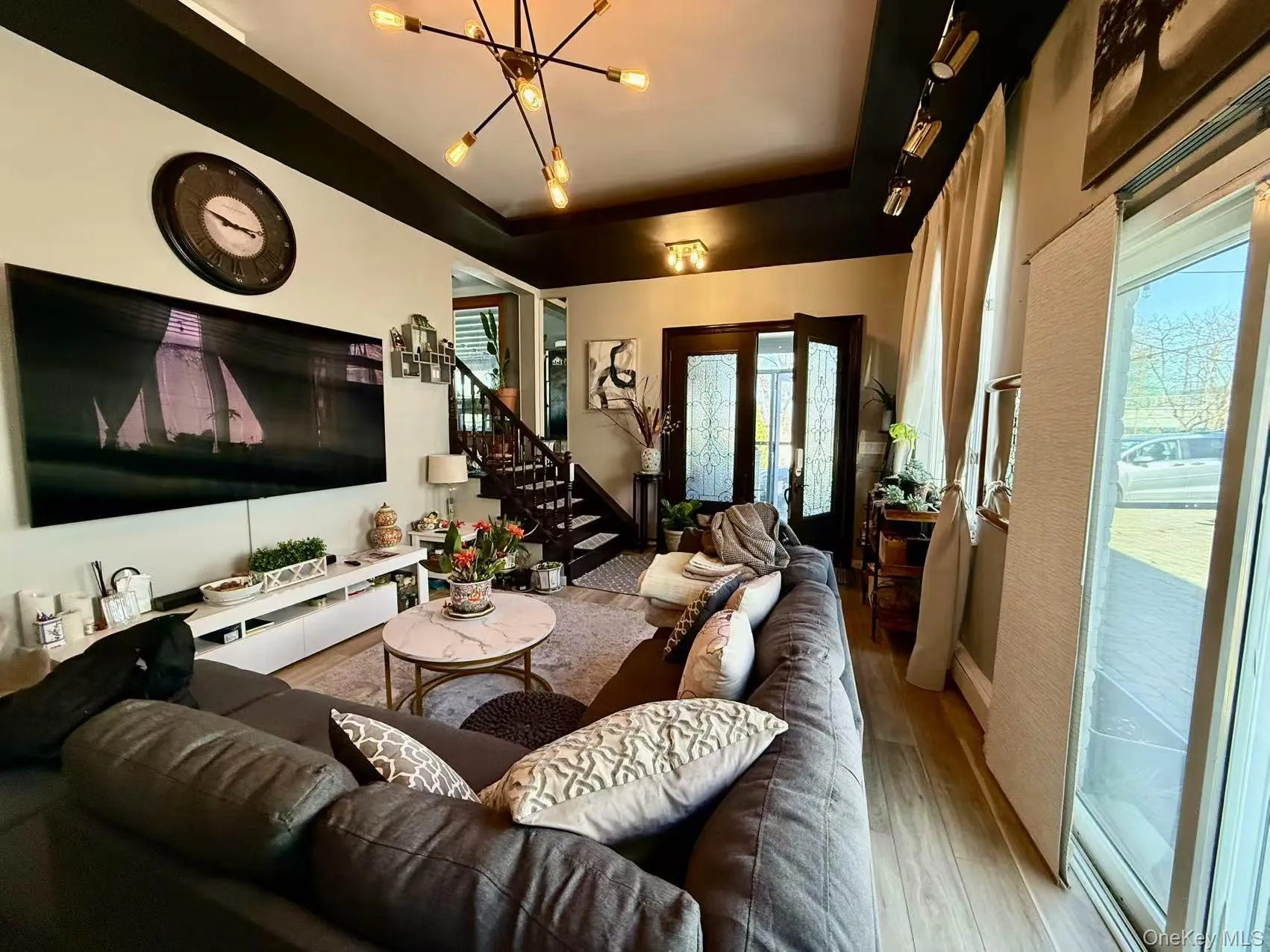 Living area with wood finished floors, a raised ceiling, stairway, and a chandelier Living area with wood finished floors, a raised ceiling, stairway, and a chandelier