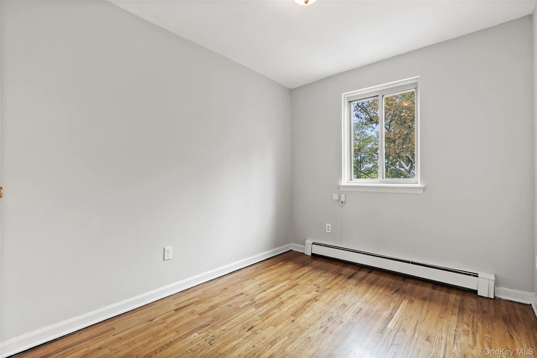 Spare room featuring a baseboard heating unit and light wood-style flooring Spare room featuring a baseboard heating unit and light wood-style flooring
