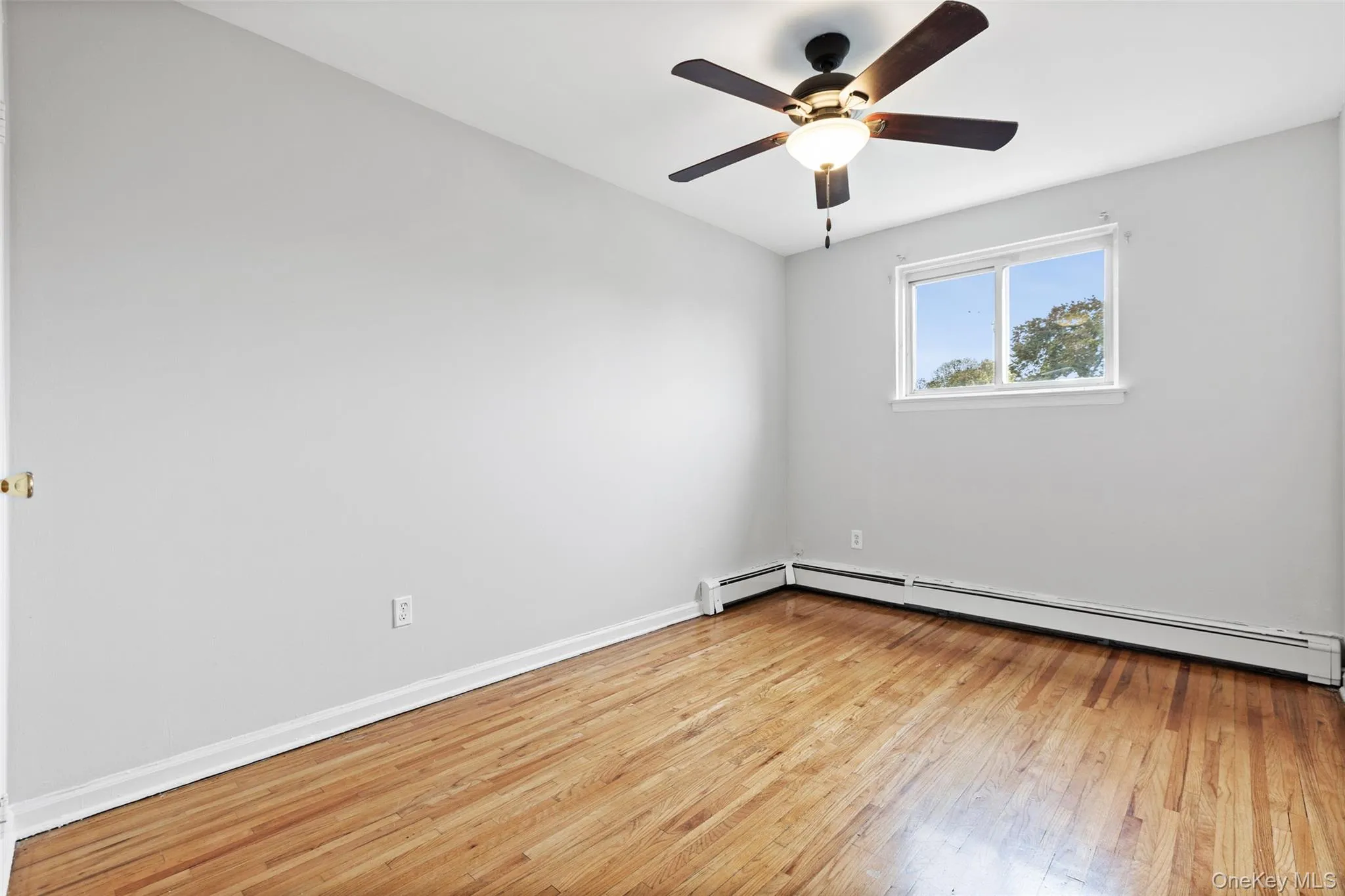 Spare room featuring light wood-type flooring, baseboard heating, and ceiling fan Spare room featuring light wood-type flooring, baseboard heating, and ceiling fan