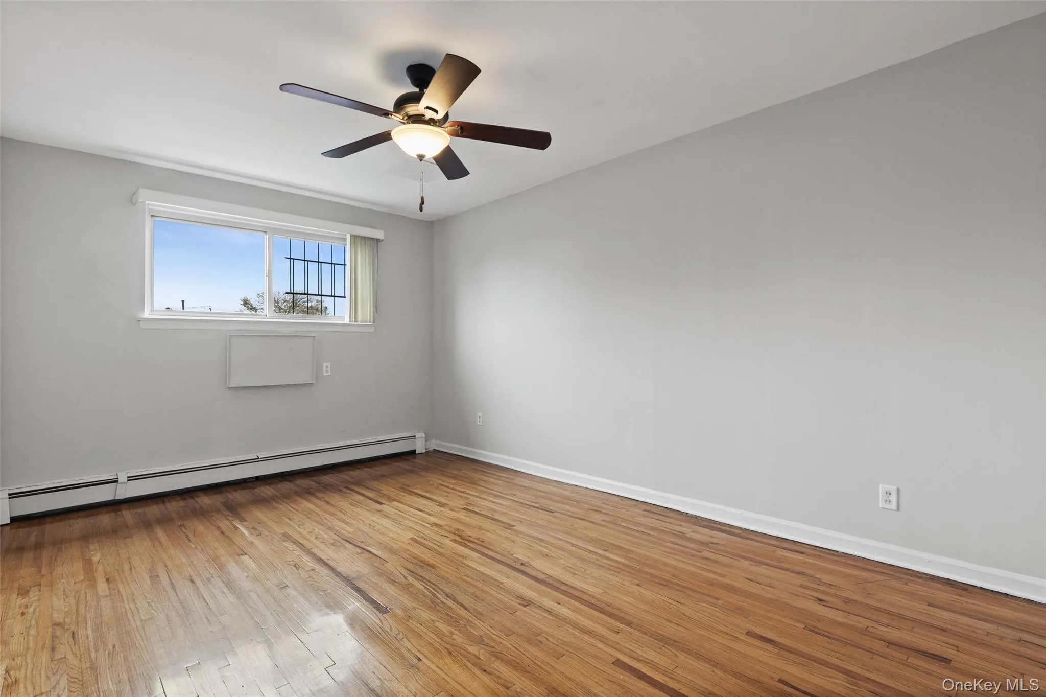 Spare room featuring light wood-type flooring, a baseboard radiator, and a ceiling fan Spare room featuring light wood-type flooring, a baseboard radiator, and a ceiling fan